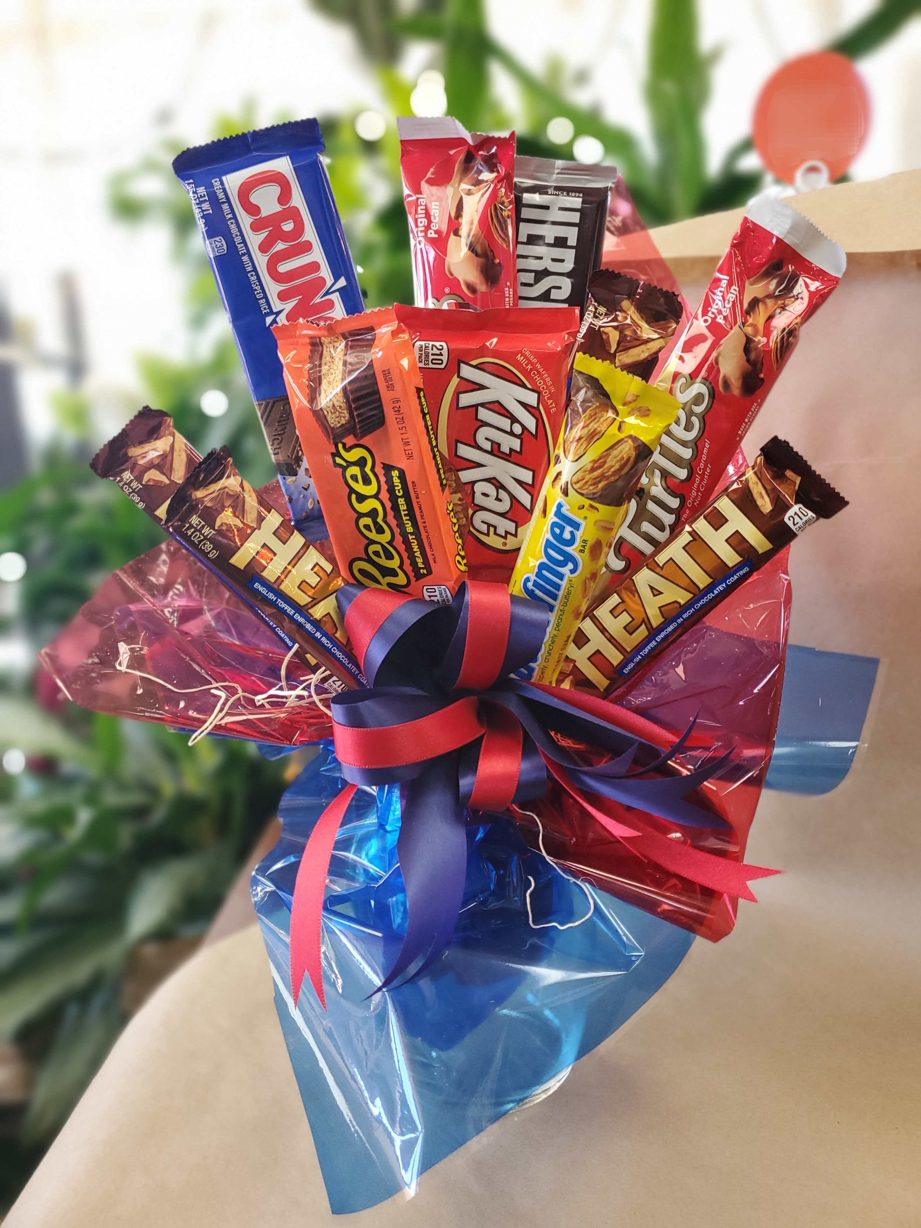 Assorted chocolate candy bars wrapped in colorful cellophane with a ribbon bow