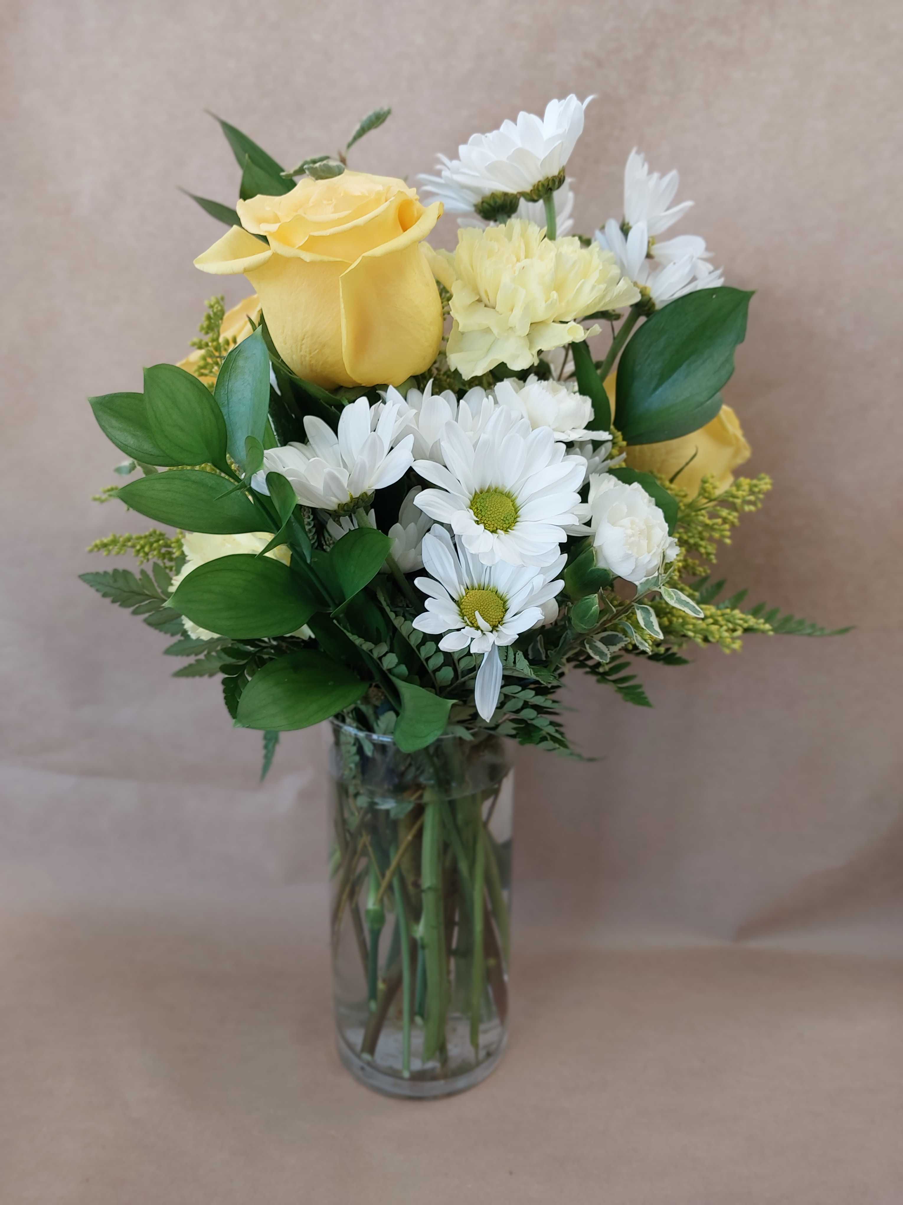 Yellow roses and white daisies in a clear glass vase