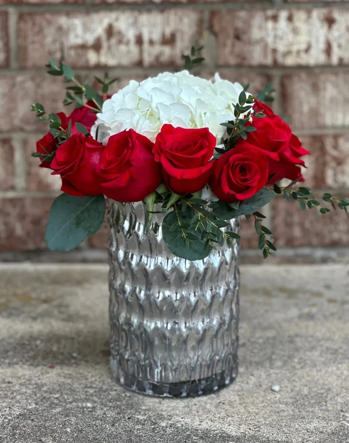 Red roses and white hydrangea in a clear glass vase