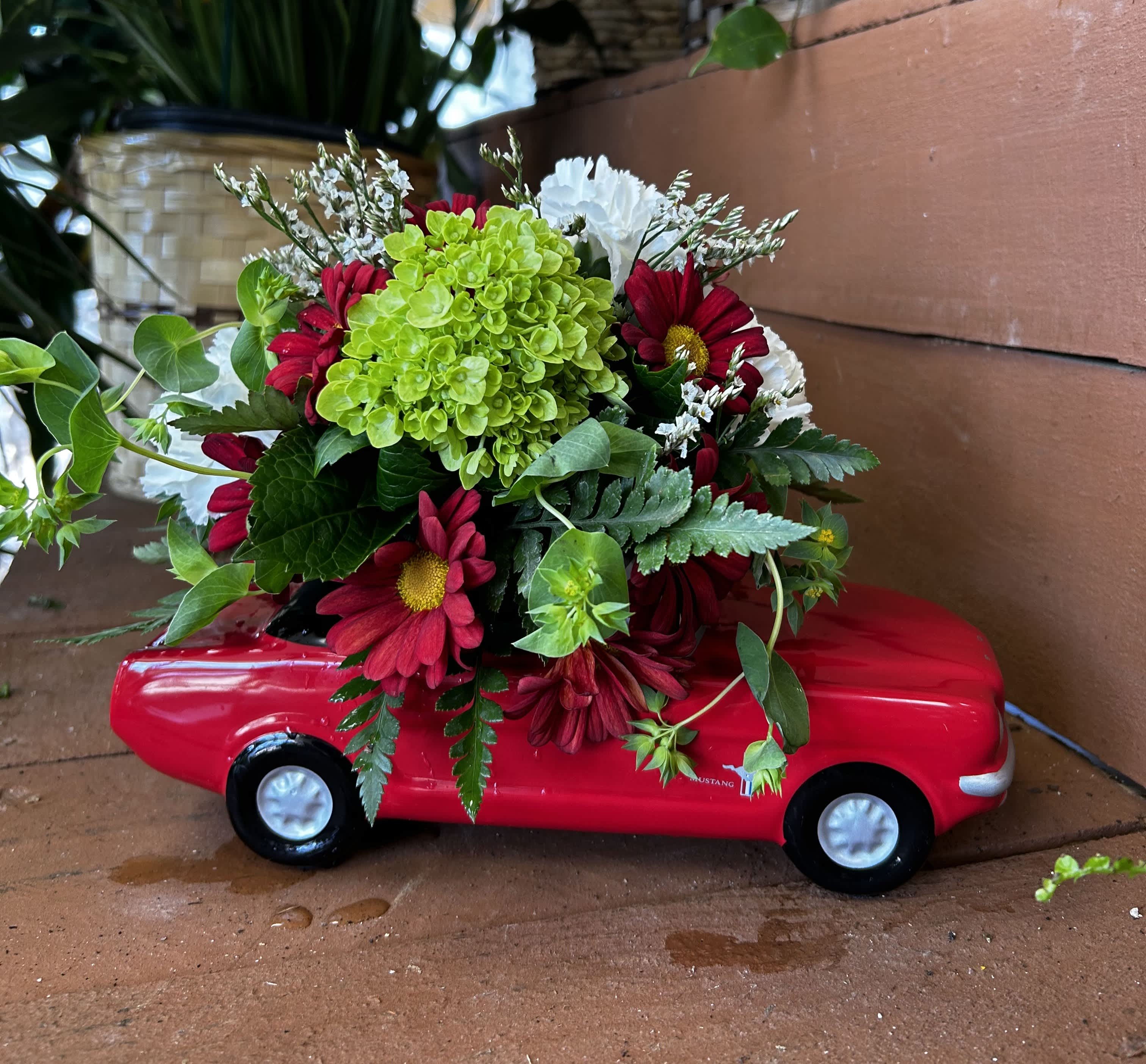 Red flower arrangement in a toy car planter
