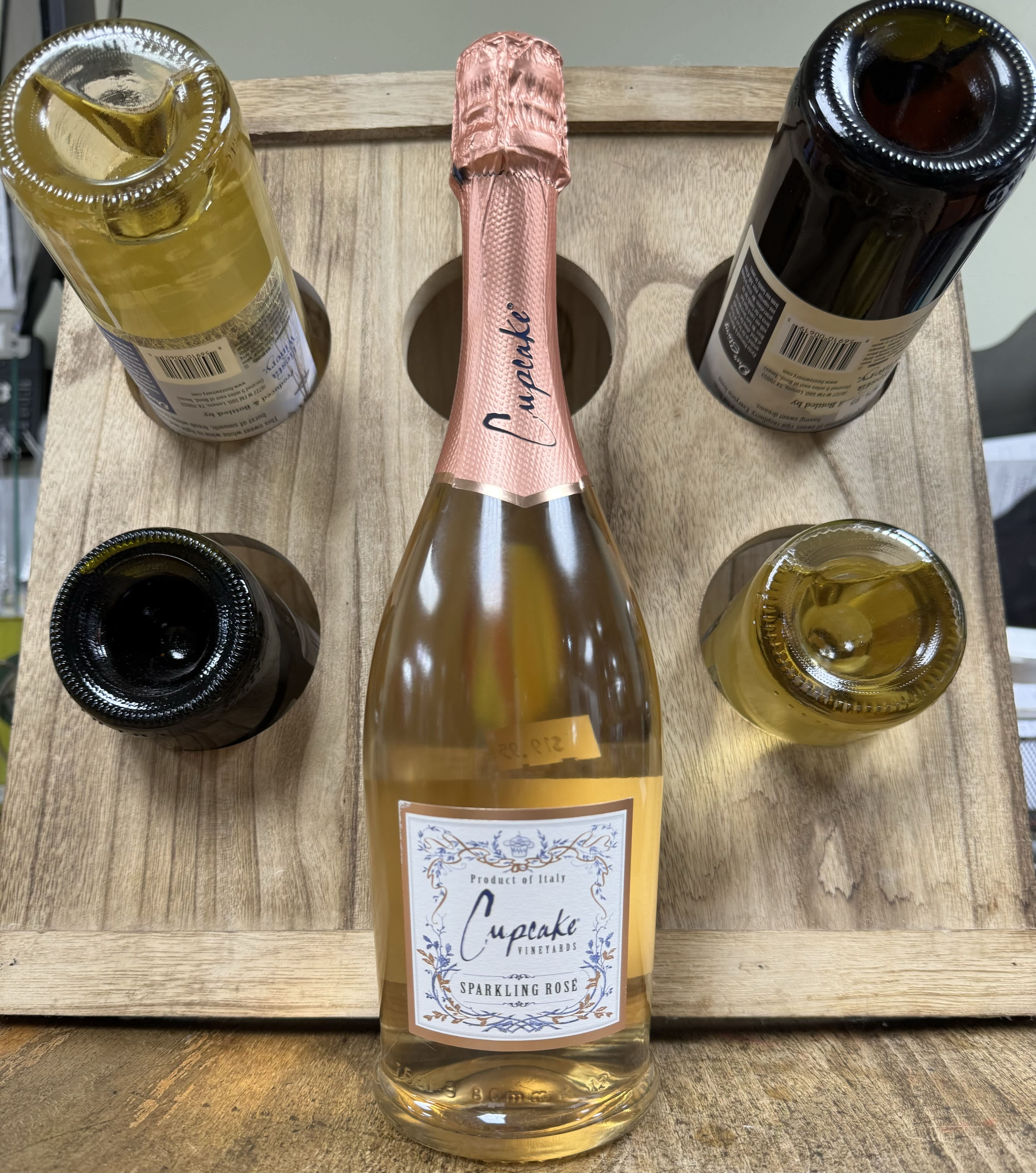 Five bottles of sparkling wine arranged in a wooden carrier