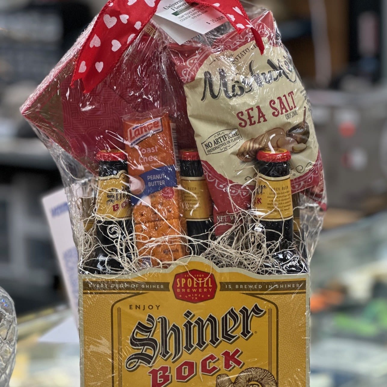 Gift basket with beer bottles, snacks, and a bag of chips wrapped in cellophane