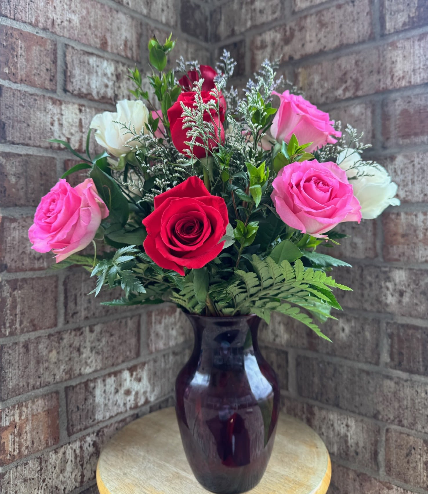 Pink, red, and white roses arranged in a dark glass vase