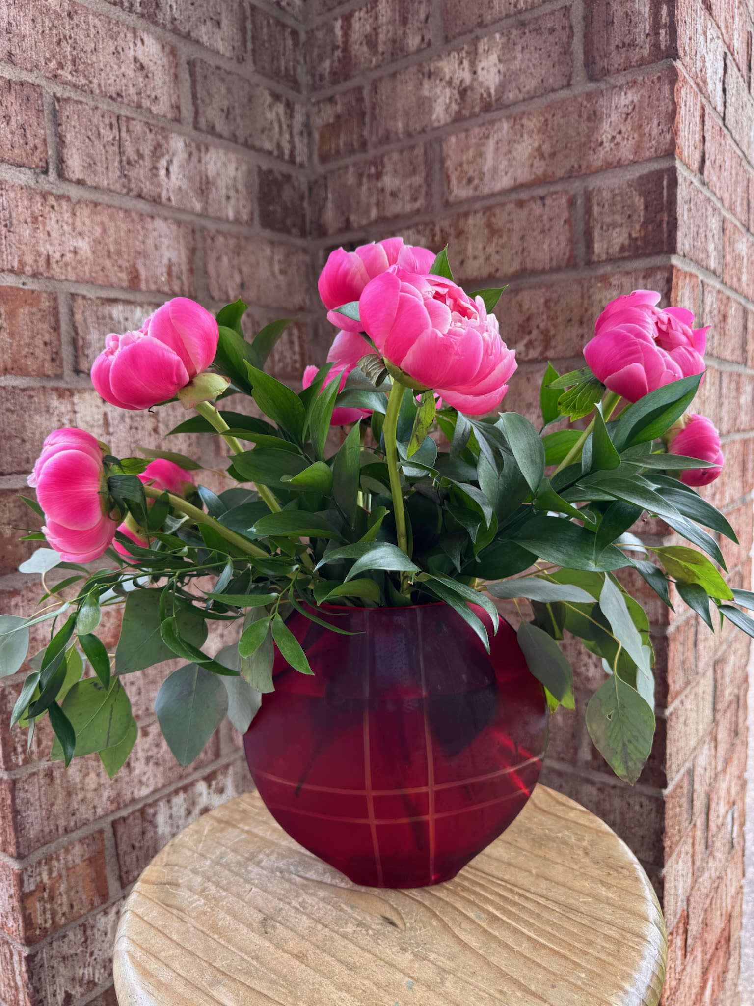 Pink peonies arranged in a red glass vase