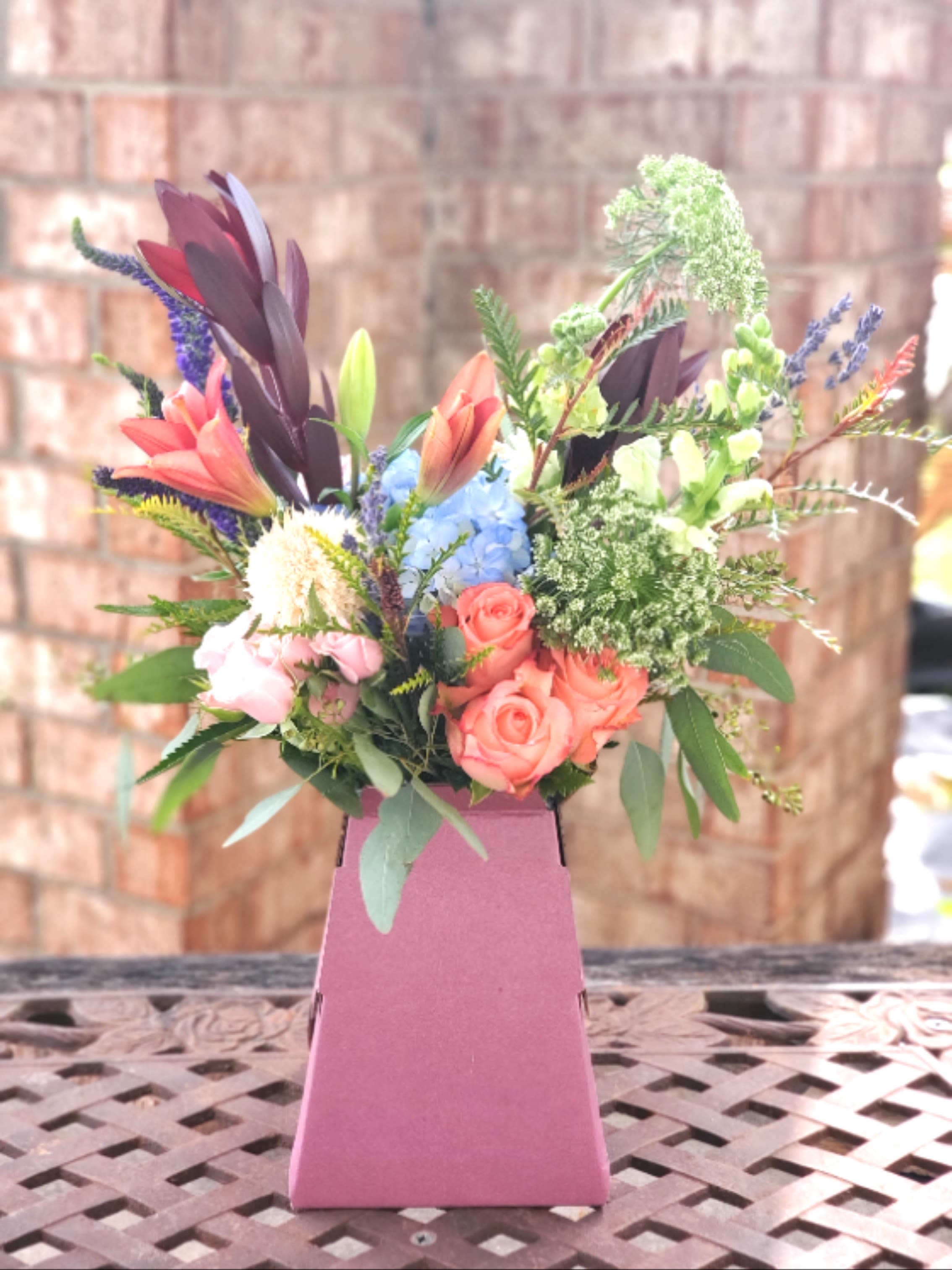 Just Say Yes - Inspired by modern style and wedding bouquets, this arrangement uses rustic colors of roses, snapdragons, and veronica in a recyclable cardboard vase.