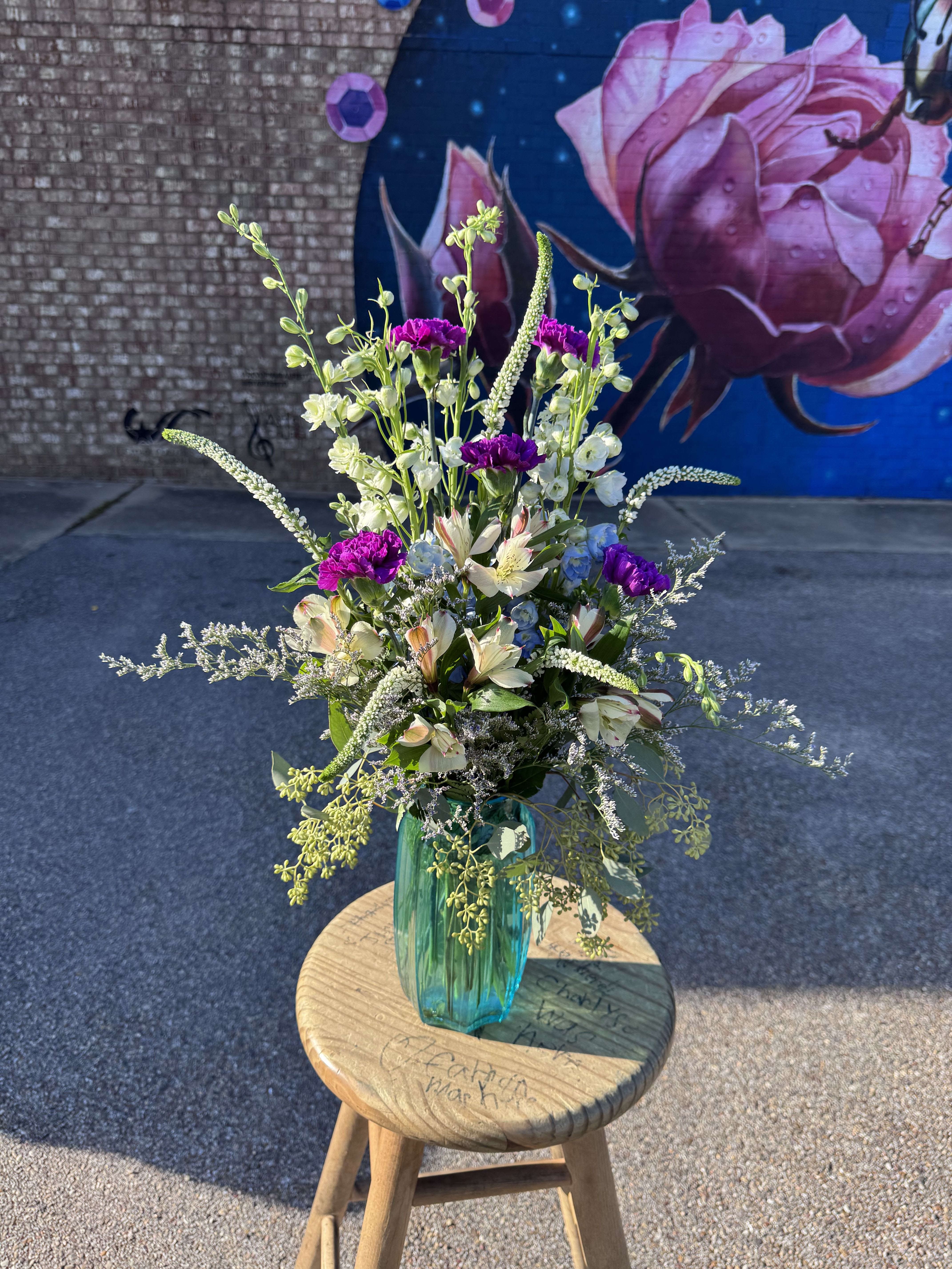 Tall mixed bouquet in a teal glass vase with pink and white blooms
