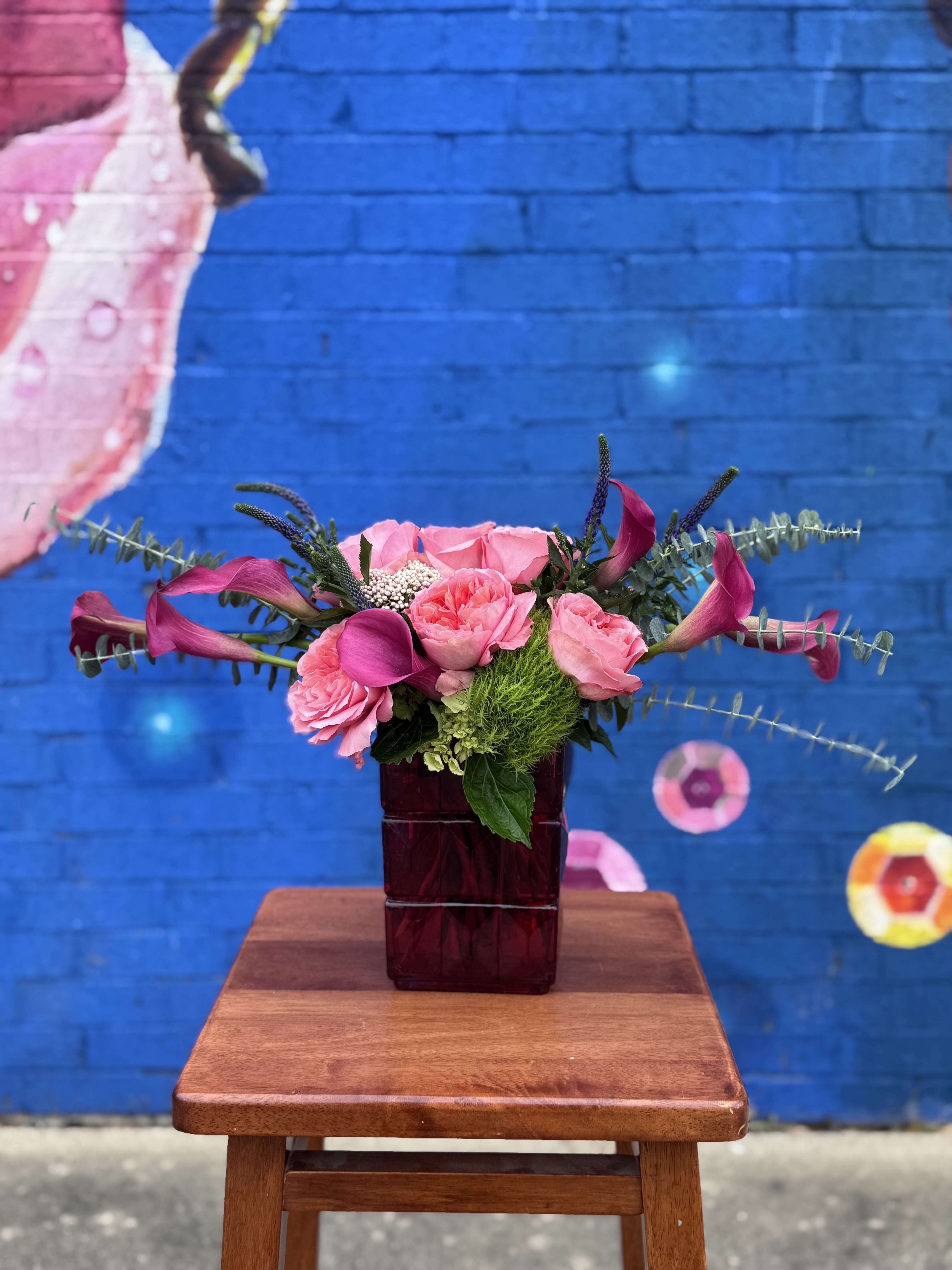 Pink roses and calla lilies in a dark glass vase