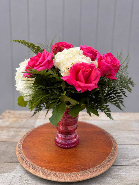 Southern Charm  - Southern Charm  A timeless nod to grace, beauty, and the kind of love that feels like home.  Designed in a classic clear glass milk jug vase, Southern Charm features lush white hydrangeas paired with hand-selected roses for an arrangement that is both elegant and heartfelt. Choose her favorite rose color to make it uniquely hers, with options including pink, red, yellow, mixed, or lavender.  Standard includes eight roses and three white hydrangeas. Deluxe includes twelve roses and four white hydrangeas.  Thoughtfully designed for Mother’s Day, this arrangement is a beautiful way to celebrate the women who bring warmth, love, and charm into our lives.