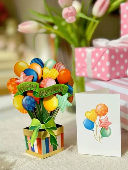 Birthday balloon bouquet in a striped gift box with a greeting card
