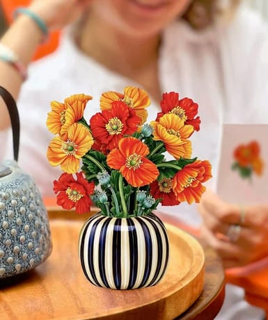Orange and red flowers in a striped ceramic vase on a table