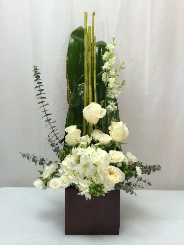 Tall white floral arrangement in a dark square vase