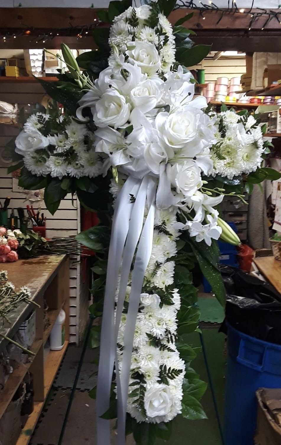Faith Cross - An all white tribute, this white cross funeral spray is pure and tranquil. Featuring a variety of white flowers, this elegant easel compliments the beauty of life. 