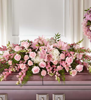 Pink floral casket spray with lilies, roses, and carnations