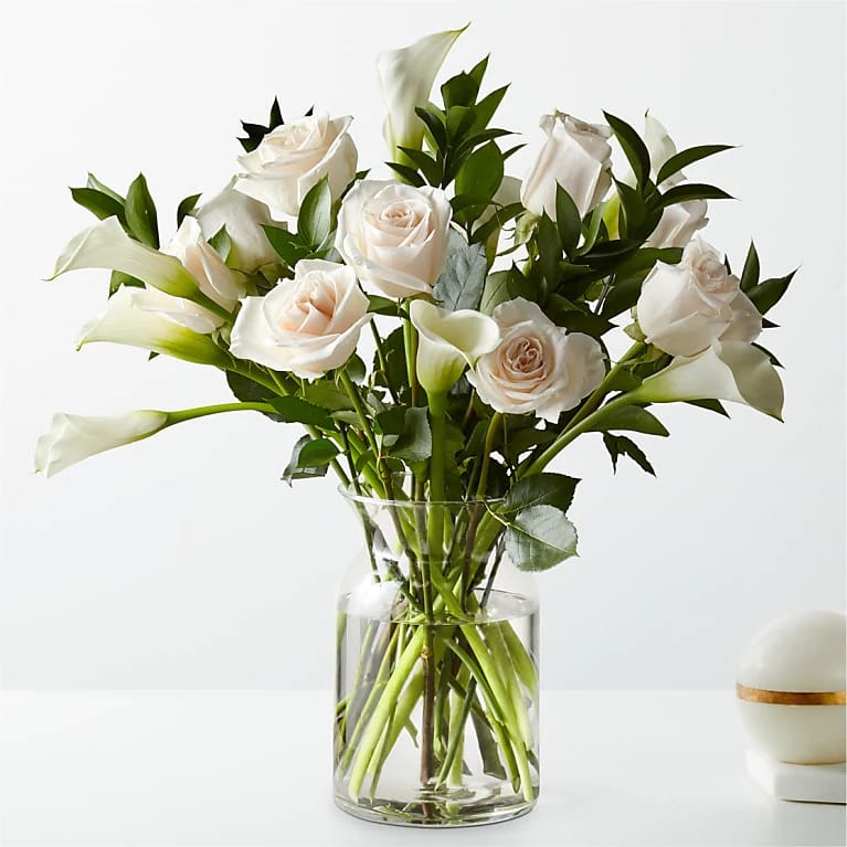 White roses and calla lilies in a clear glass vase