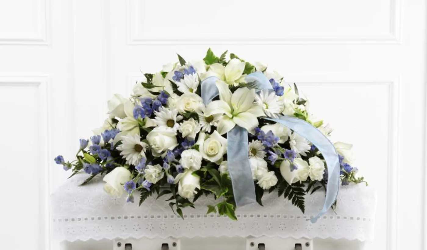 White and blue funeral casket spray with ribbon