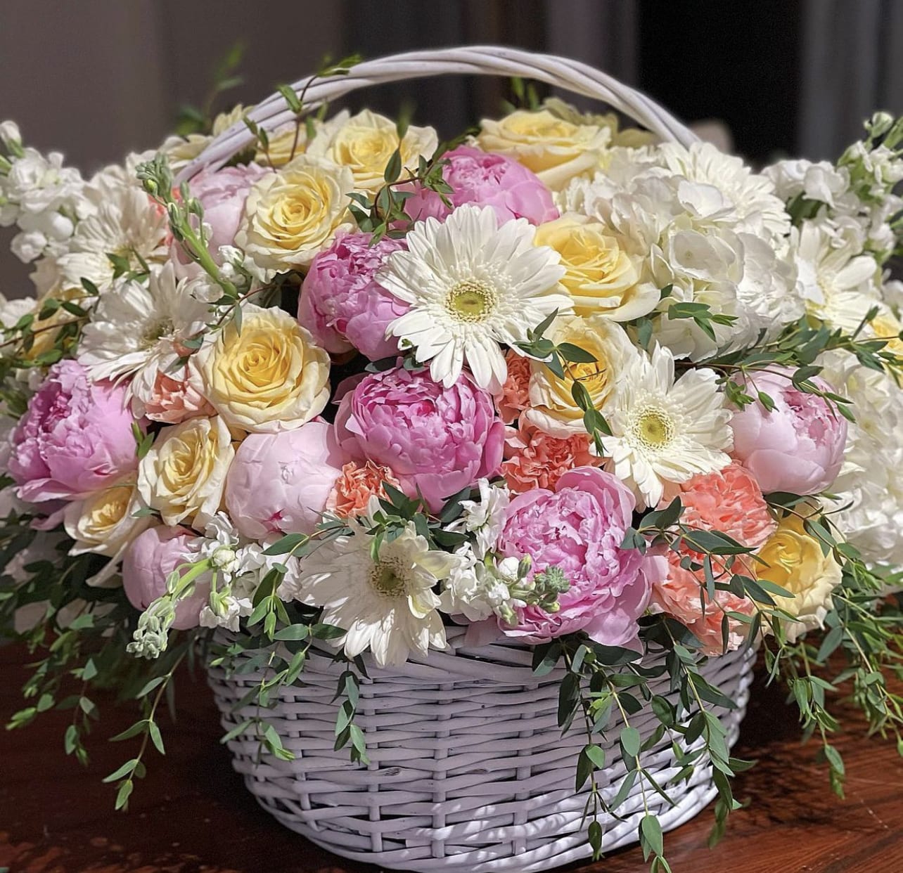 Basket of pink and yellow roses with white daisies