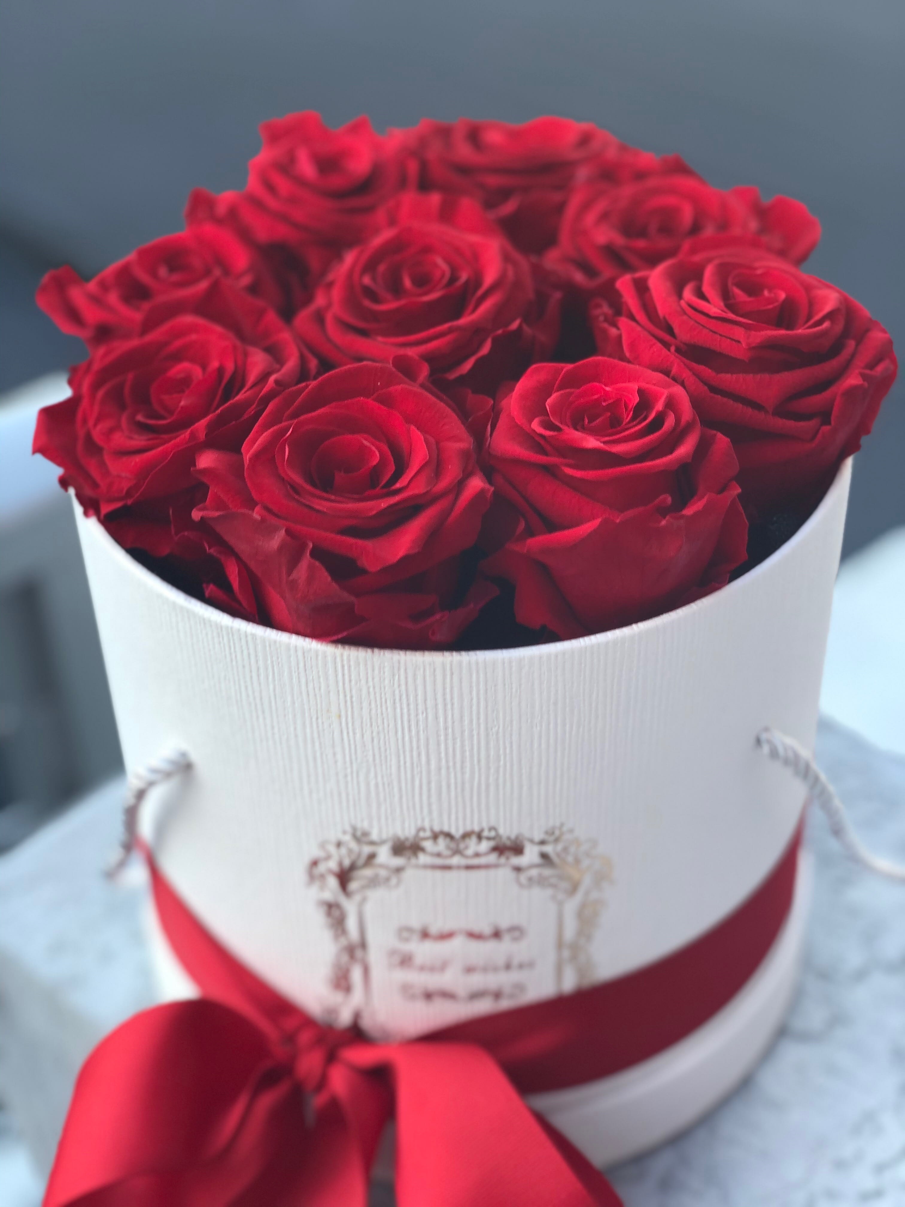 Red roses arranged in a white round box with a red ribbon