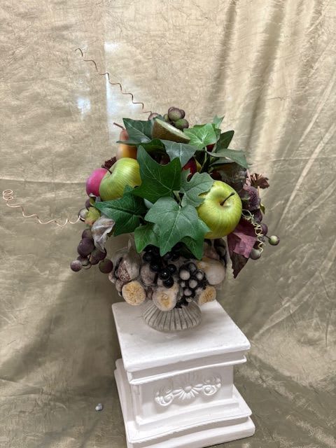 Fruit arrangement with apples and grapes in a decorative vase