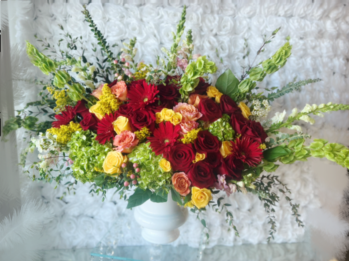A Celebration Of Life  - Elegant design of bright colors. A Celebration Of Life. Upgrades of this design will give a bigger fuller arrangement in same urn container. As shown this arrangement is approx 19" tall x 33" wide This design can be arranged In glass vase. Perfect for any occasion.