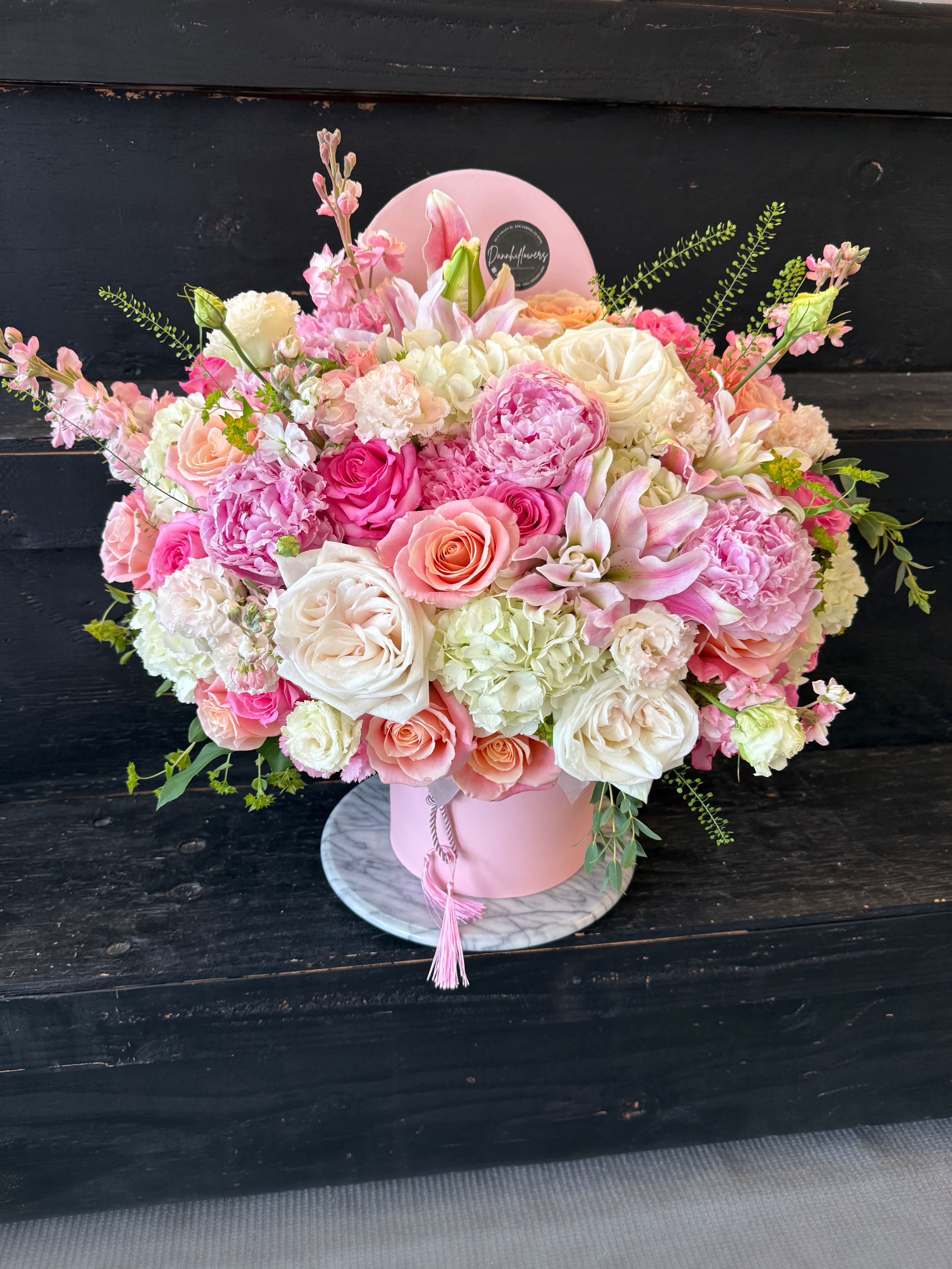 Pink and white mixed flower arrangement in a round pink box
