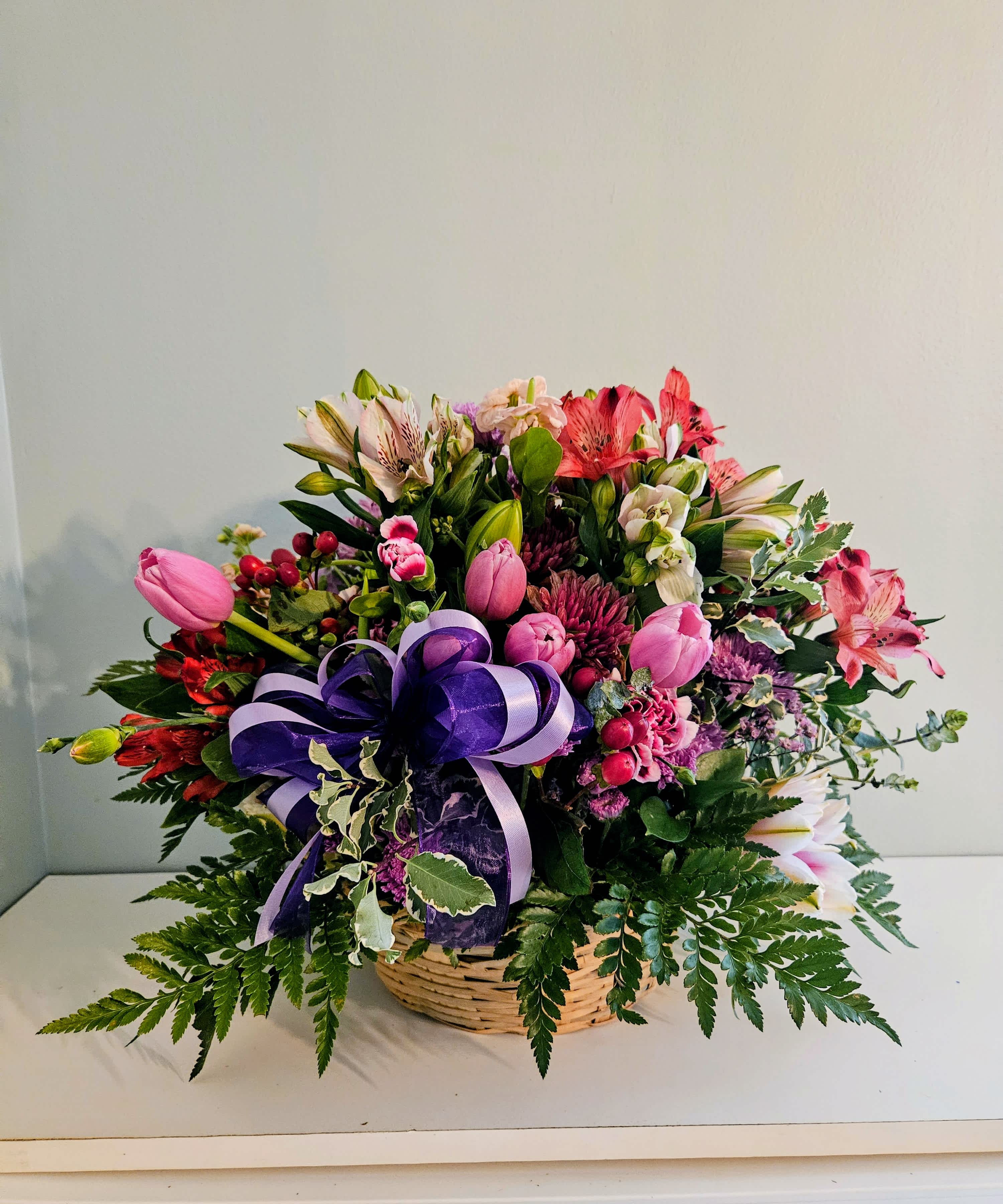 Mixed flower basket with pink, purple, and white blooms and a purple ribbon