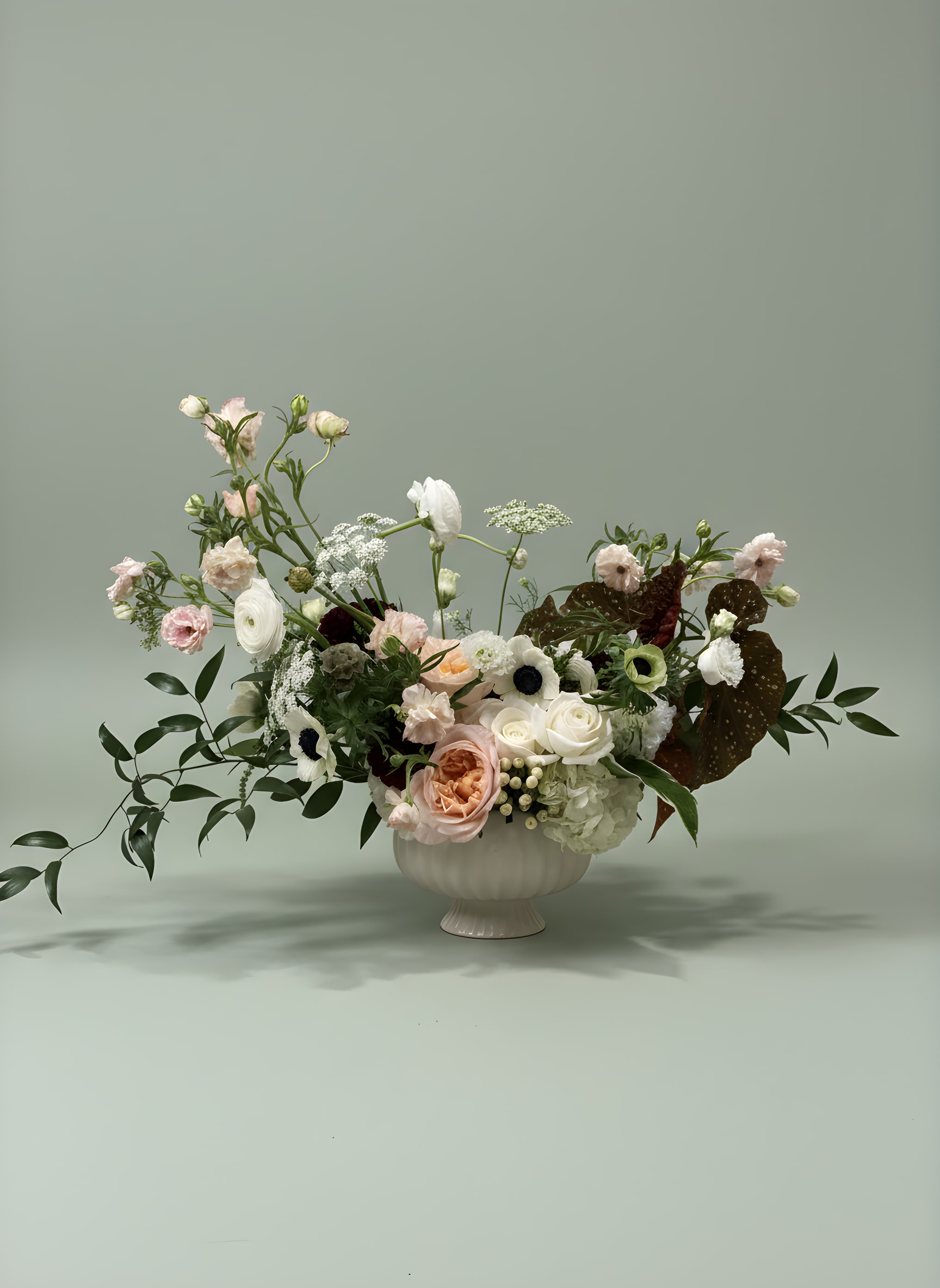 Mixed pastel floral arrangement in a white pedestal vase