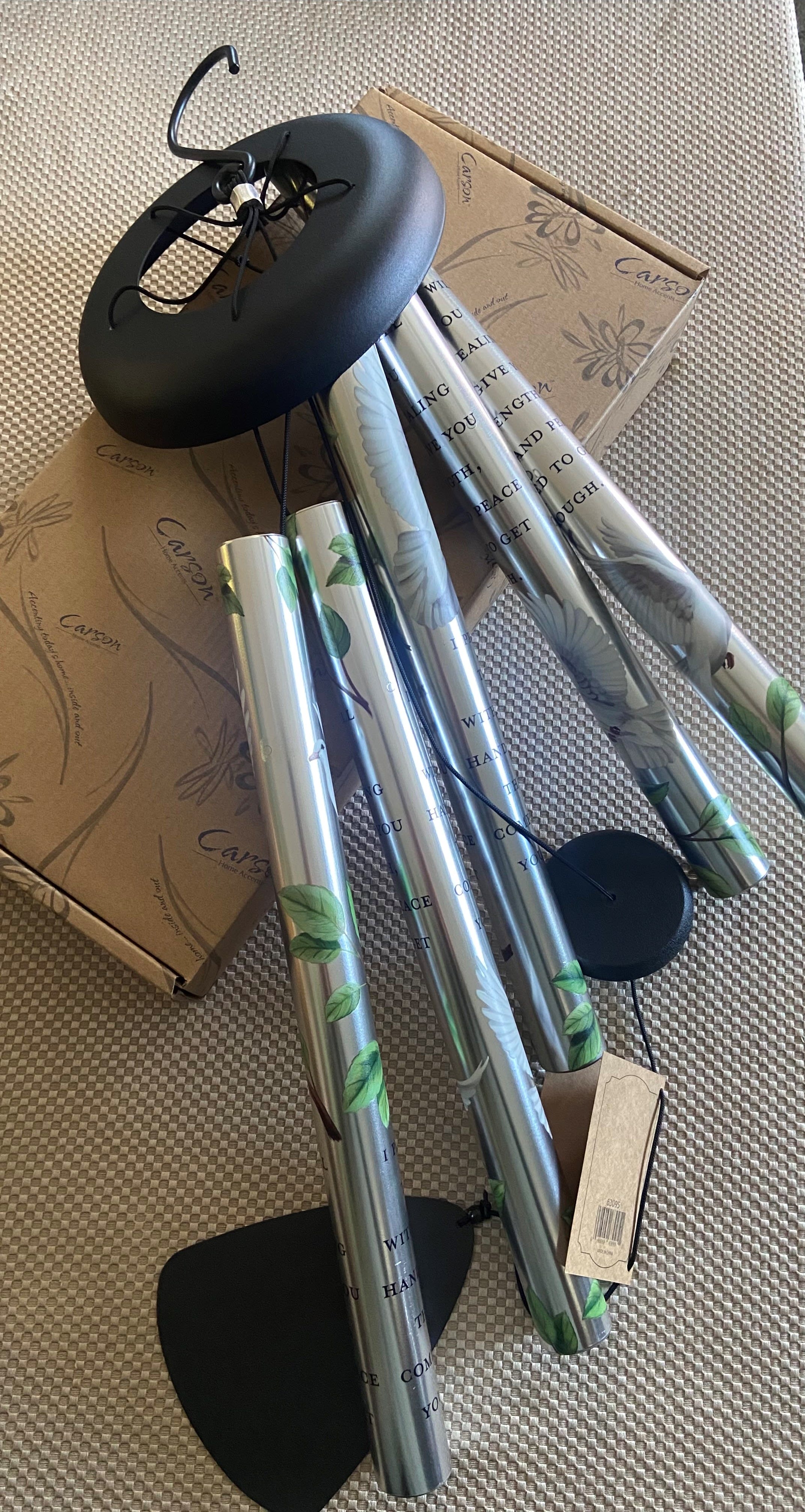 Silver wind chimes with black hanging parts and a cardboard box
