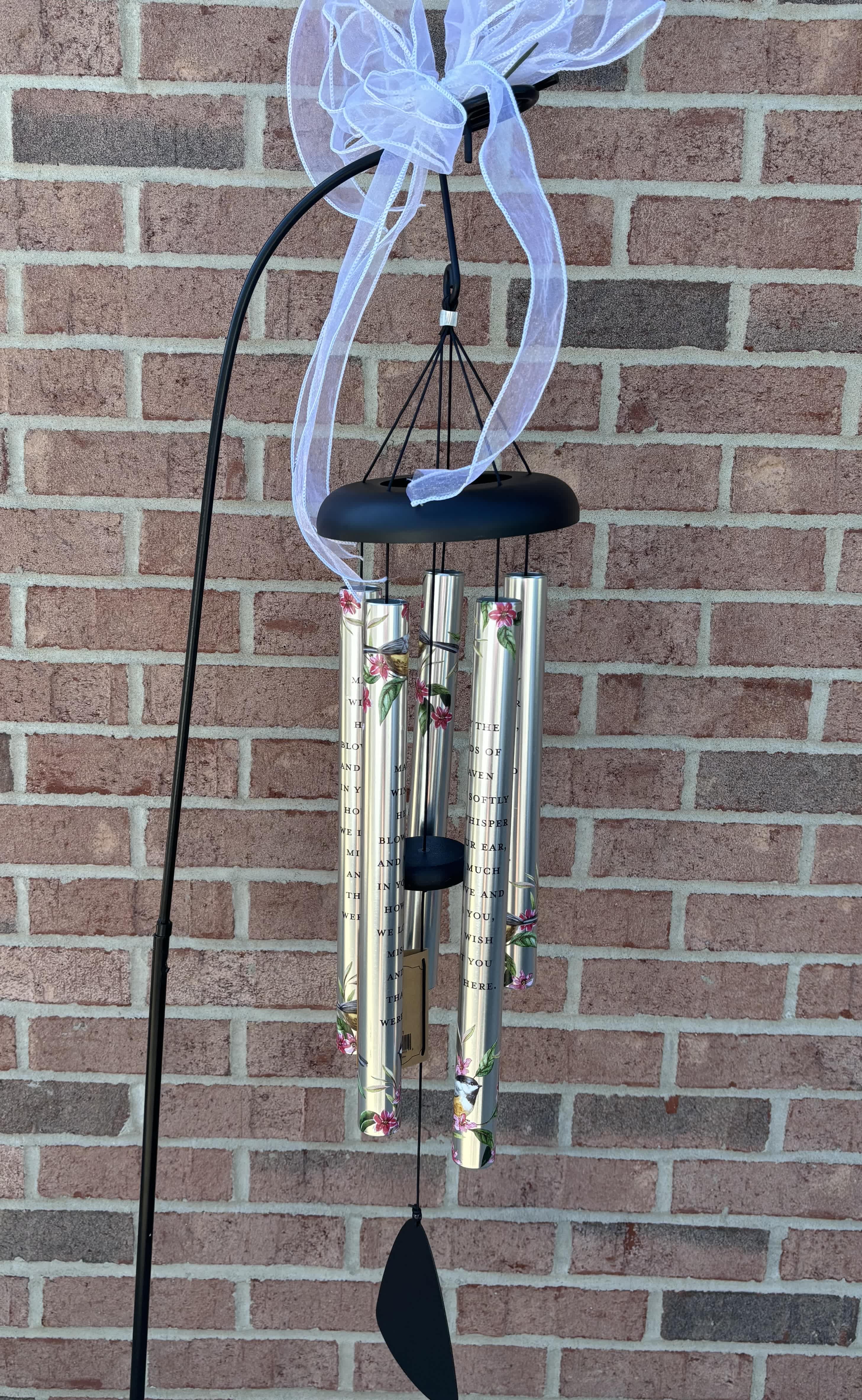 Black wind chime with silver tubes and a white ribbon bow