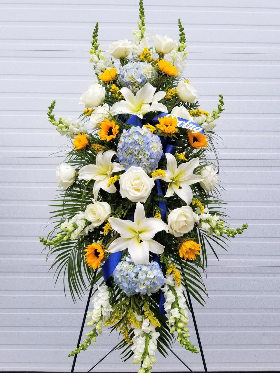 Tall standing floral spray with white lilies, roses, hydrangeas, and sunflowers
