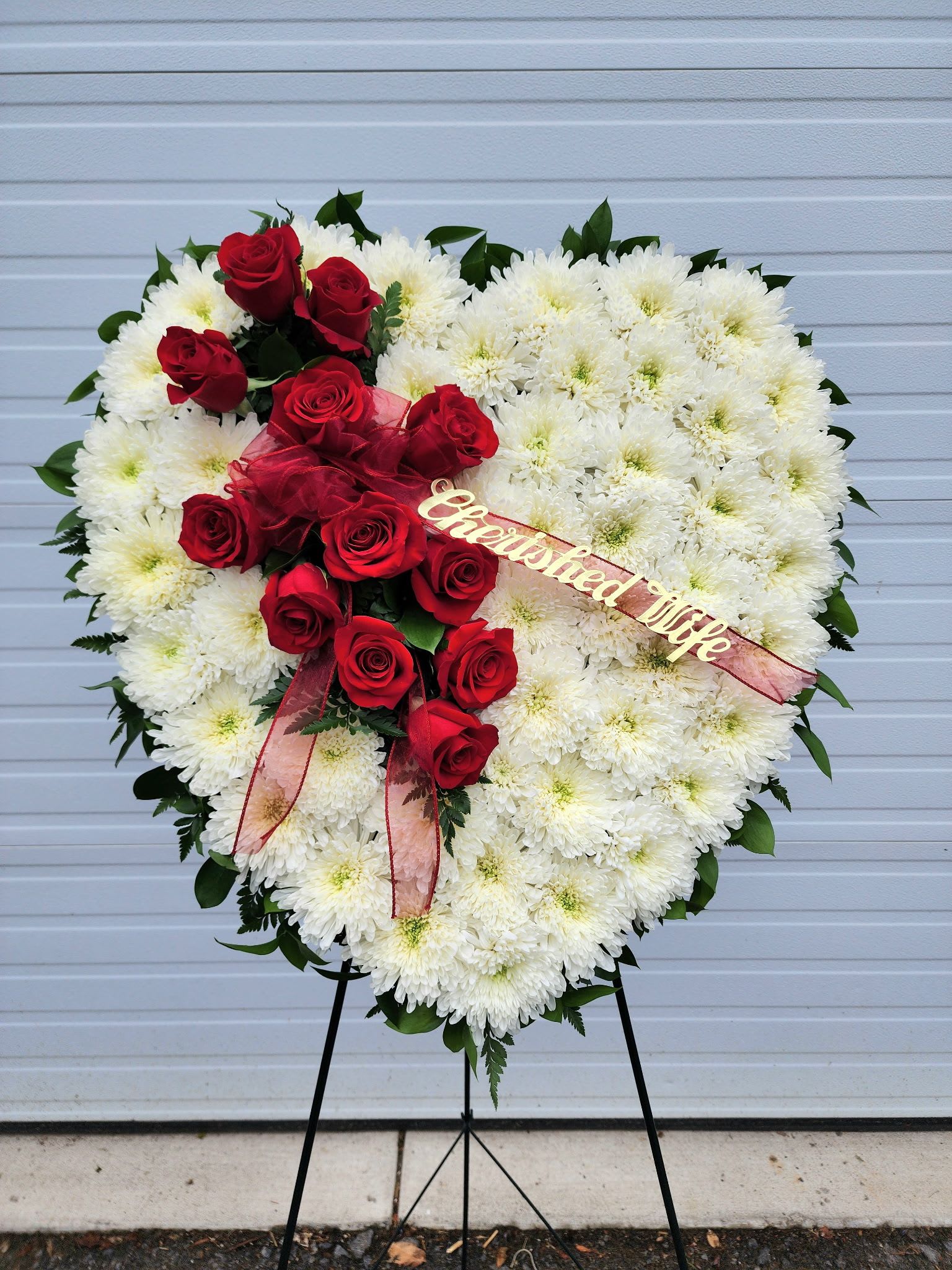 Heart-shaped white chrysanthemum wreath with red roses and ribbon