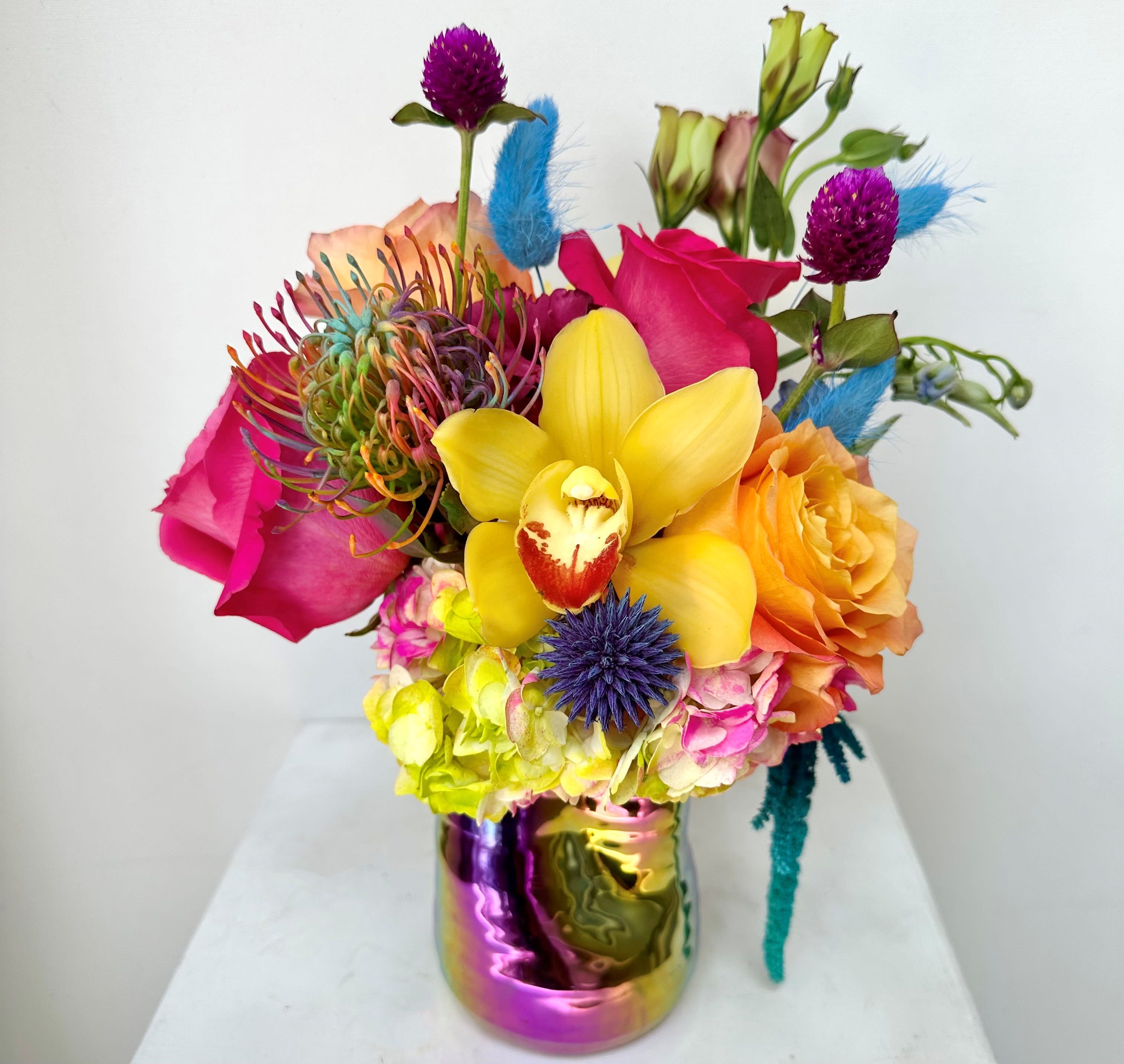 Bright mixed bouquet with orchids, roses, and calla lilies in a metallic vase