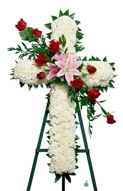 Cross-shaped floral tribute with white blooms, red roses, and a pink lily