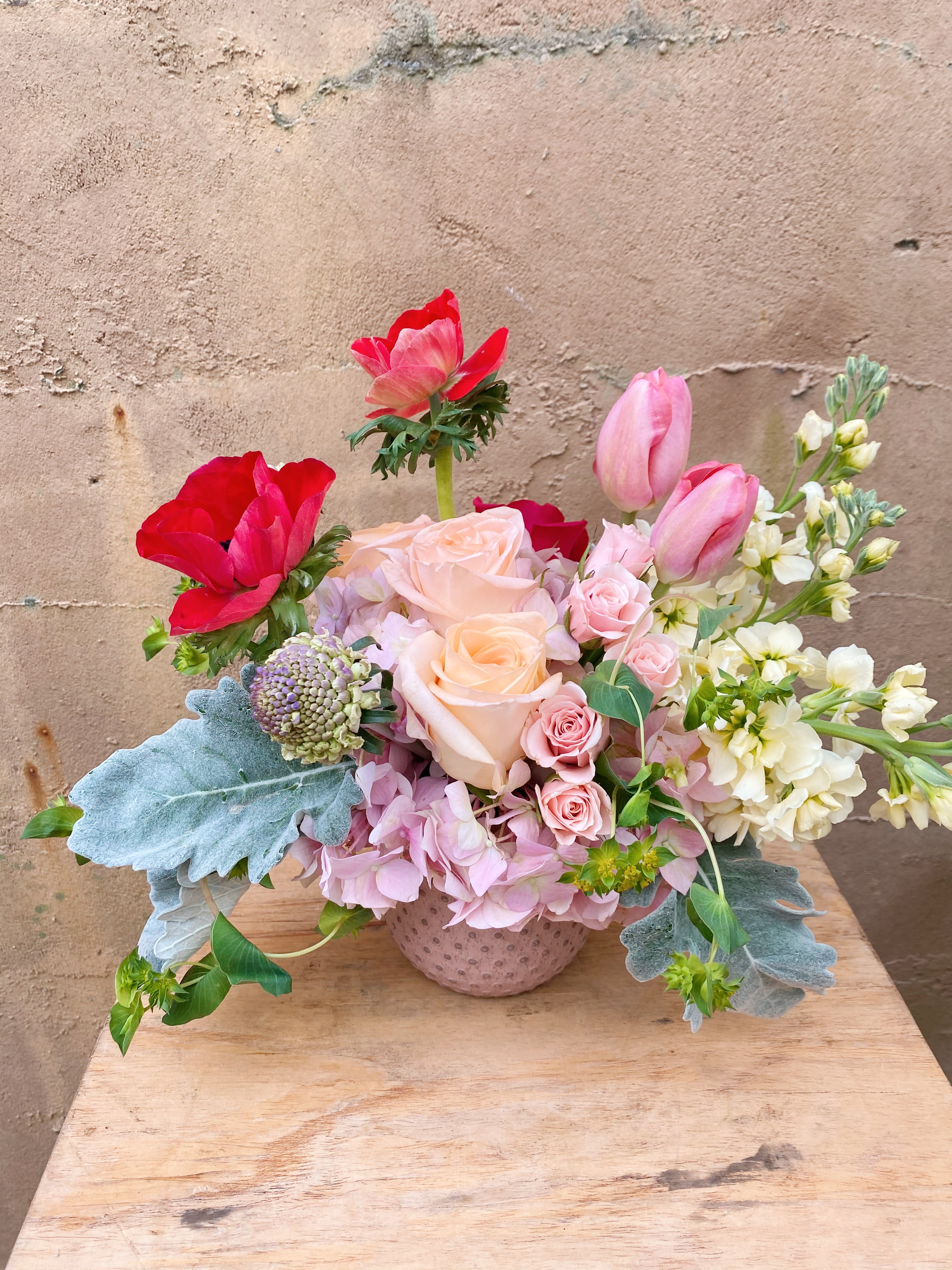 Pink and red floral arrangement in a textured vase