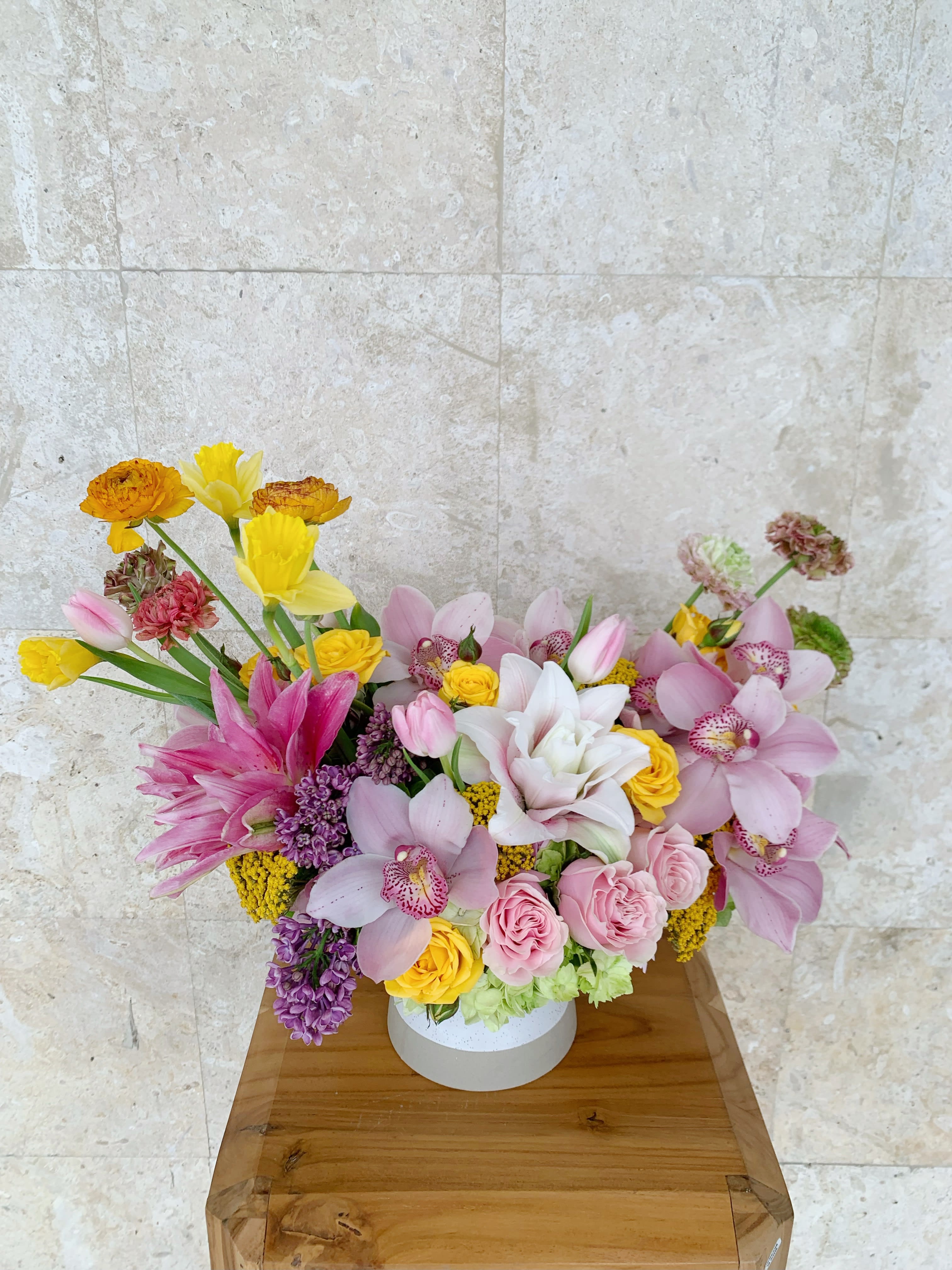 Mixed bouquet of pink, yellow, and white flowers in a round white box