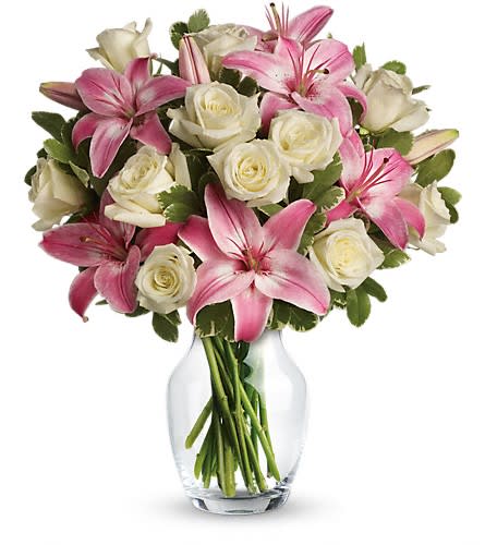 Arrangement of pink lilies and white roses in a clear glass vase