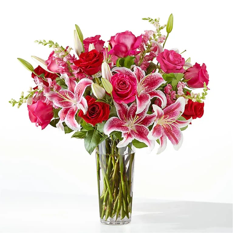 Love in Full Bloom - A vibrant and captivating arrangement featuring rich red and hot pink roses paired with elegant pink lilies, beautifully designed in a clear glass vase. Bursting with color and charm, this stunning display blends the timeless beauty of roses with the graceful elegance of lilies, creating a gift that is both sophisticated and unforgettable. Perfect for celebrating love, friendship, birthdays, anniversaries, or any occasion that calls for a touch of floral luxury.
