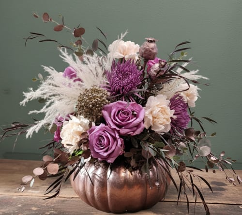 Purple and cream floral arrangement in a copper pumpkin vase