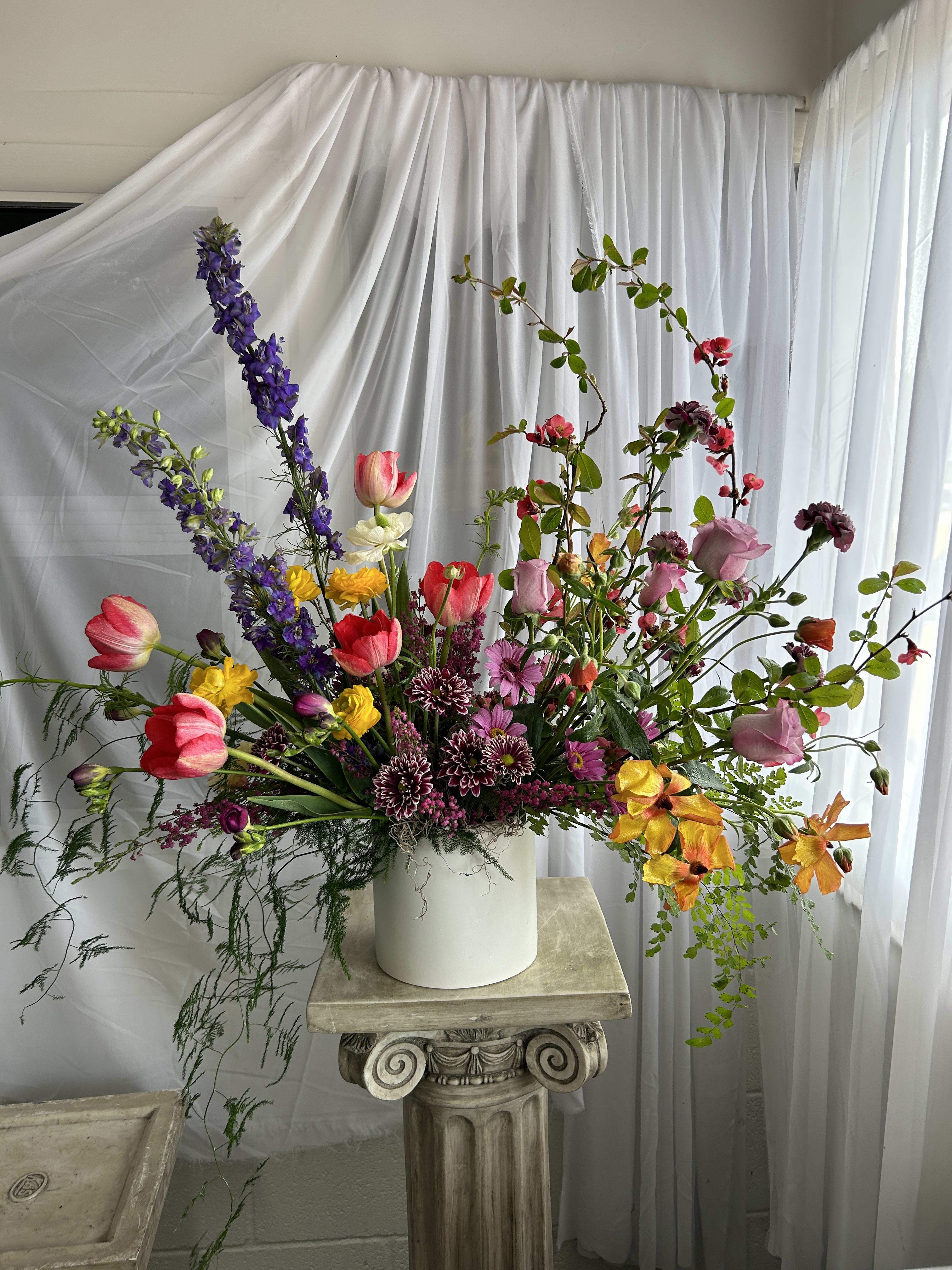 Tall mixed bouquet in a white vase with pink, purple, and yellow flowers