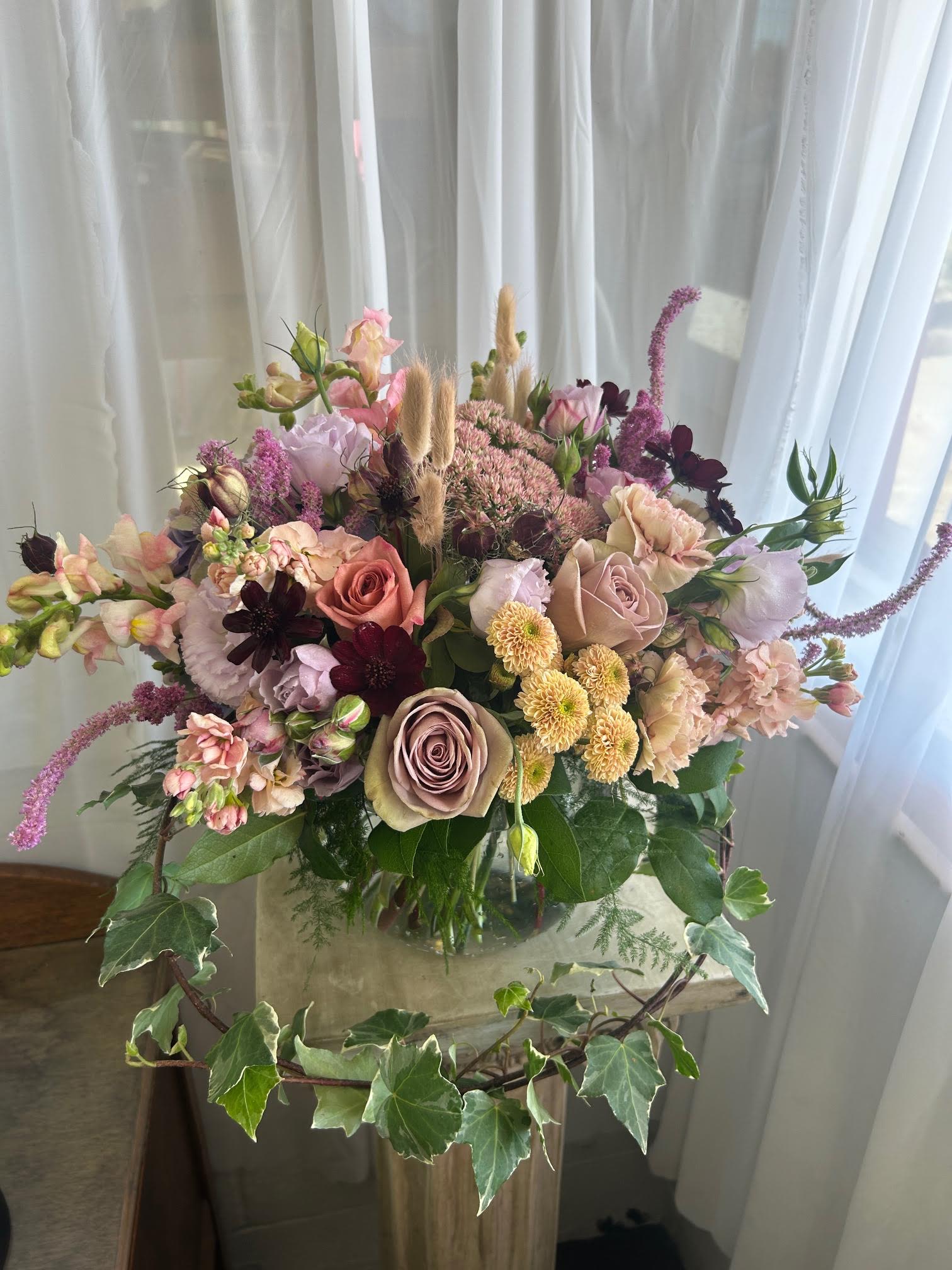 Mixed bouquet of roses, carnations, and small blooms in a glass vase
