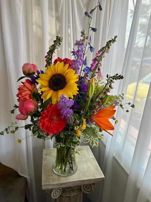 Colorful mixed bouquet in a clear glass vase with a sunflower and lilies