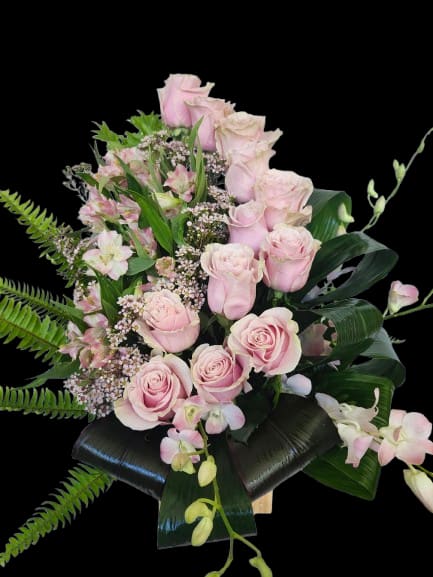 Pink dream - Soft pink roses and pale pink alstroemeria form the heart of this floral arrangement, a romantic birthday bouquet or anniversary gift that reads as gentle and thoughtfully personal. White filler blooms and soft green accents keep the composition fresh and airy, so the person you're thinking of will feel both cherished and comforted the moment they see it.  Orchids and layered foliage - long fern fronds and broad dark leaves - give the design a slightly tropical, structured contrast that keeps the look modern and lush rather than overly formal. The arrangement is hand‑styled to feel full and layered, with a mix of textures from velvety rose petals to delicate alstroemeria blooms and crisp greenery, all in a soothing palette of pink, white, and green.  Perfect for everyday gifting, "thinking of you" moments, birthdays or anniversaries, this bouquet suits someone who appreciates soft color and a relaxed, elegant feel. Care: keep flowers in fresh water, out of direct sunlight, and refresh the vase water every two days to prolong blooms.
