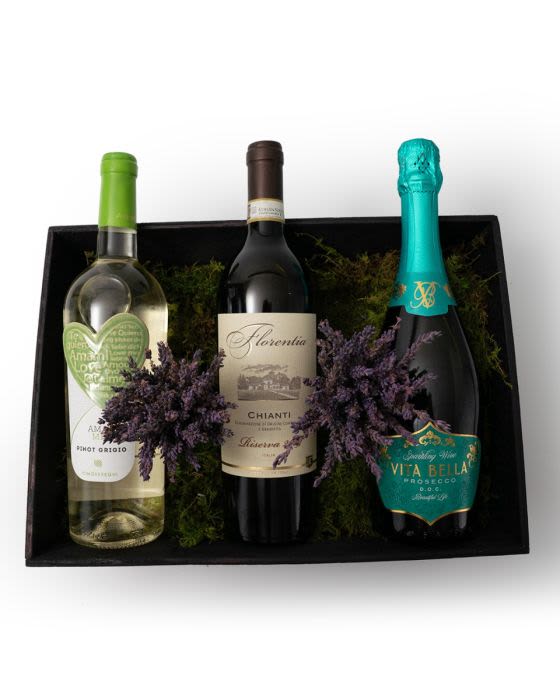 Gift box with three assorted wine bottles nestled in moss with purple dried sprigs