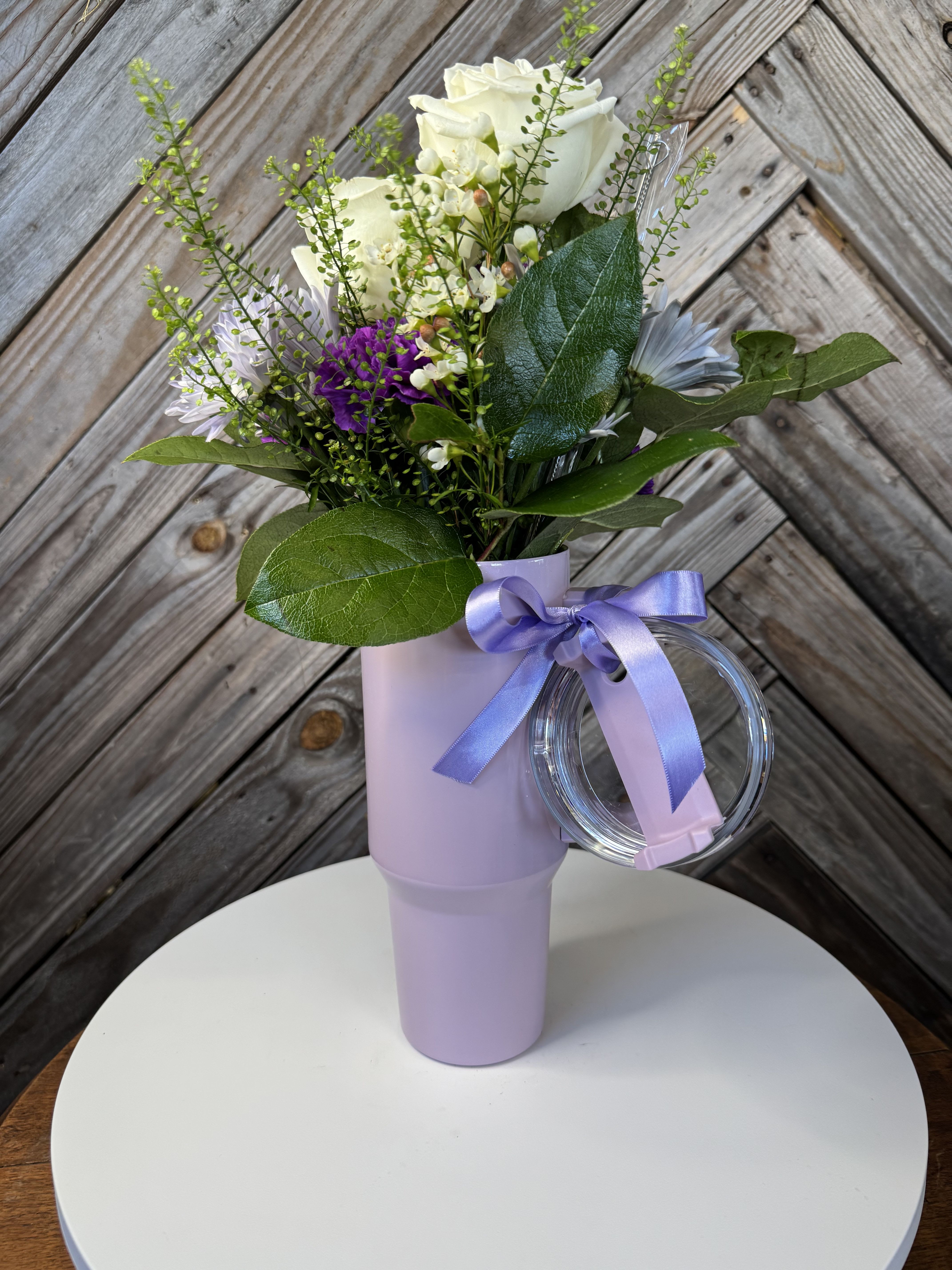 White and purple bouquet in a lavender tumbler with a ribbon
