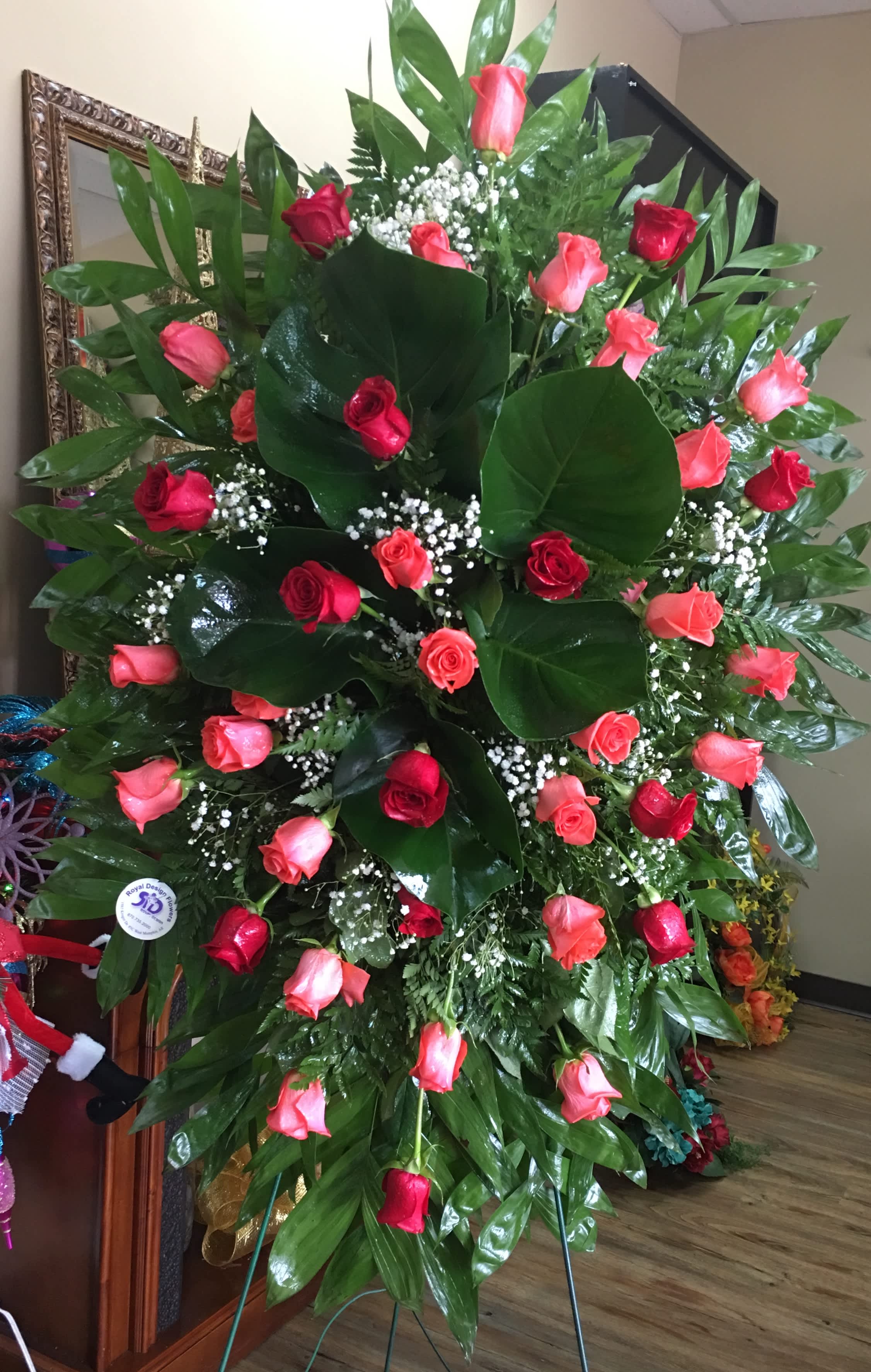 Large standing arrangement of red and pink roses with glossy greenery