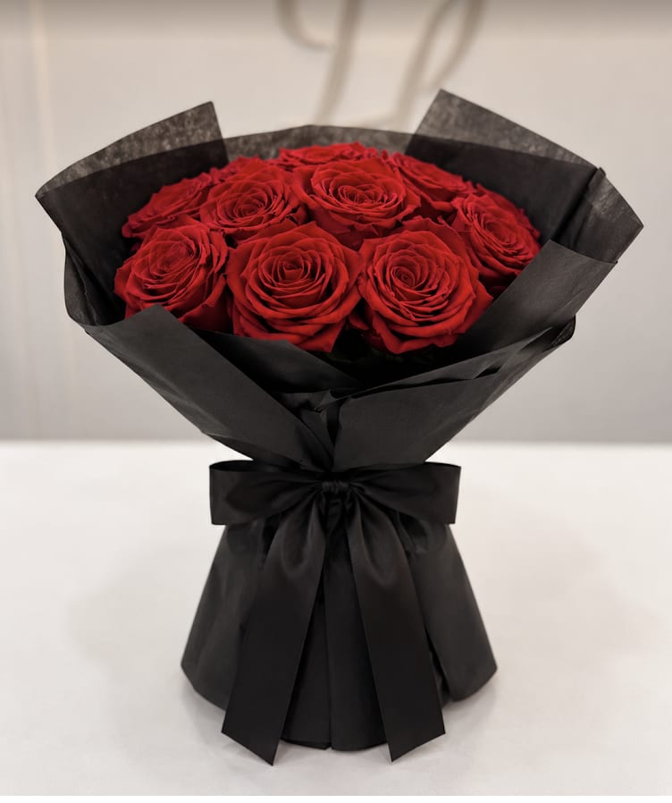 Bouquet of red roses wrapped in black paper with a black ribbon