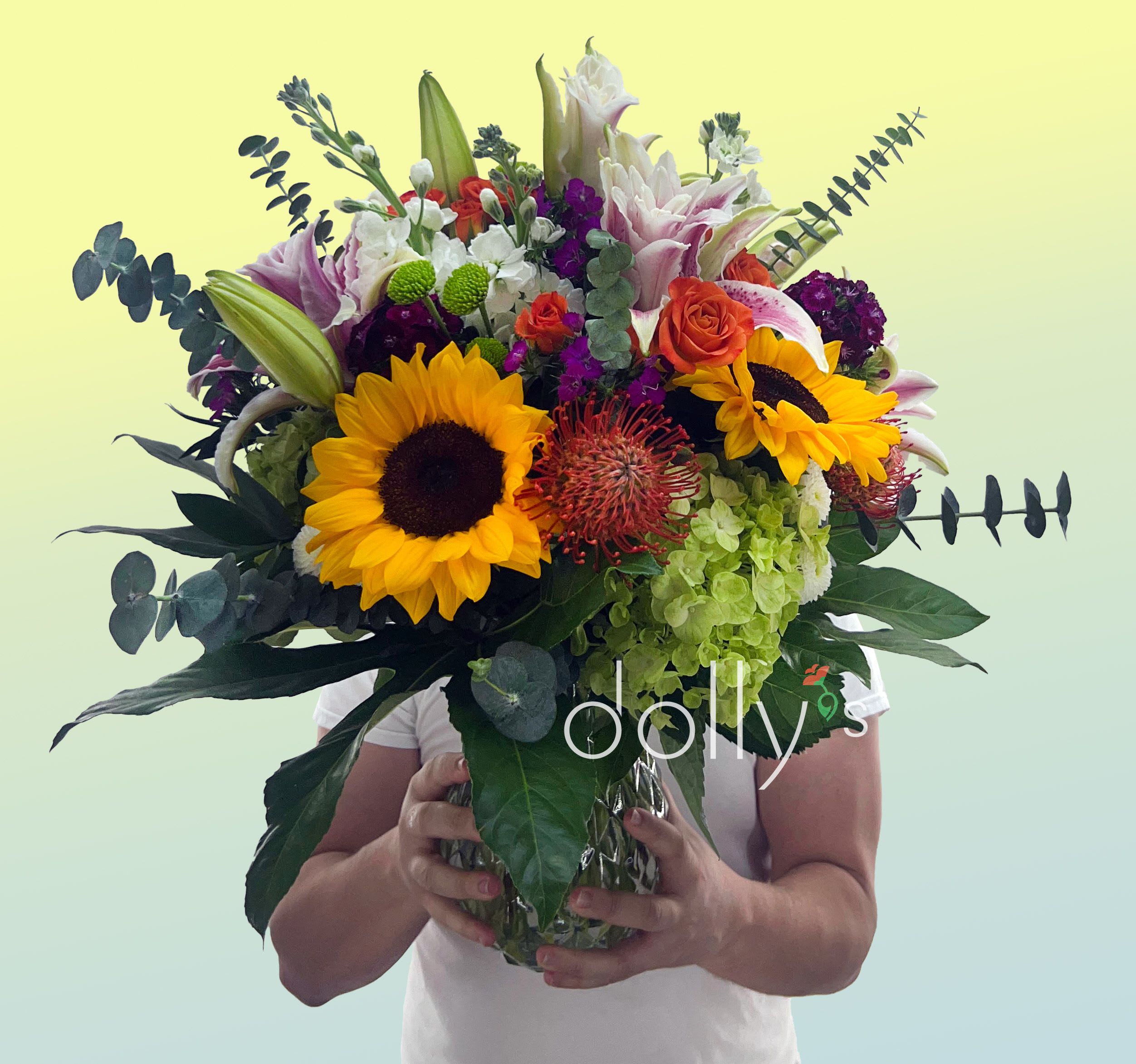 Mimo Sunset - Inspired by the vibrant, warm glow that settles over the Magic City each evening, our Mimo Sunset bouquet captures that perfect Miami "golden hour." This arrangement brings the warmth of a Florida sunset indoors. Composed of Sunflowers, Lilies, Spray Roses, Dianthus, Fresh Green Buttons, Lush Eucalyptus &amp; Seasonal Greens.