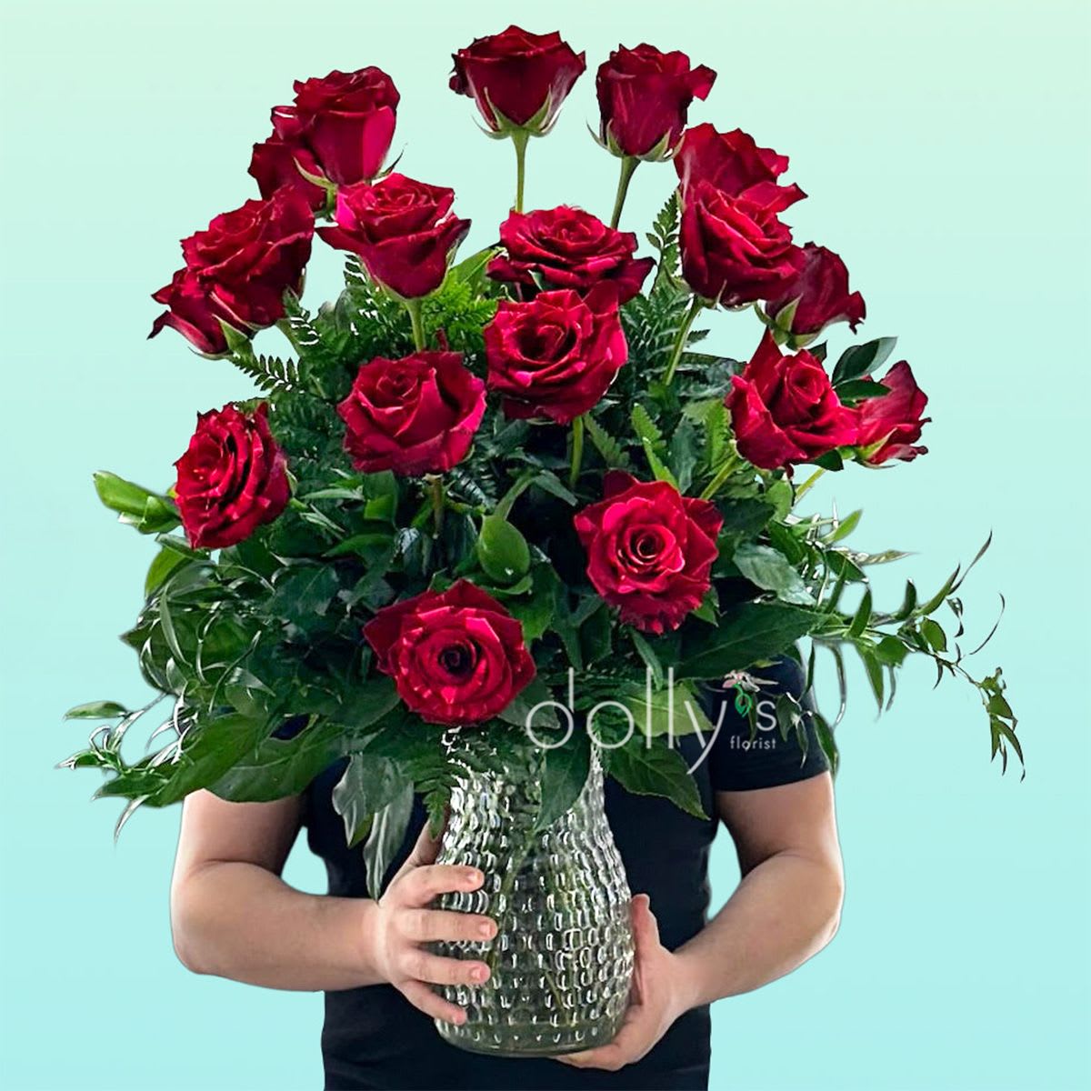 24 Red Panther Long-Stem Roses - The Red Panther rose is a striking bicolor hybrid tea rose variety renowned for its deep, velvety red petals dramatically marbled or splashed with hot pink streaks. A dramatic cluster of deep Red Panther roses creates an immediate romantic impression - the perfect birthday bouquet or anniversary roses to make the person you're thinking of feel deeply admired. This flower arrangement of 18 red roses is designed for classic gifting moments like Valentine's Day, anniversaries, or to offer sincere sympathy with quiet elegance; the upright, formal silhouette reads as both passionate and refined.  Eighteen rich red roses are arranged at varying heights to give a full, dimensional look, set in a clear textured glass vase that adds subtle pattern and weight to the presentation. Dark, glossy mixed greenery and white accents provide contrast and lift the blooms, while the dense, layered styling keeps the focus on the lush rose heads and their velvety petals.  For the recipient, this arrangement feels unmistakably special - the kind of bouquet that conveys deep affection or thoughtful remembrance. Vase-ready on arrival; refresh the water every 2-3 days and recut stems for the longest life.