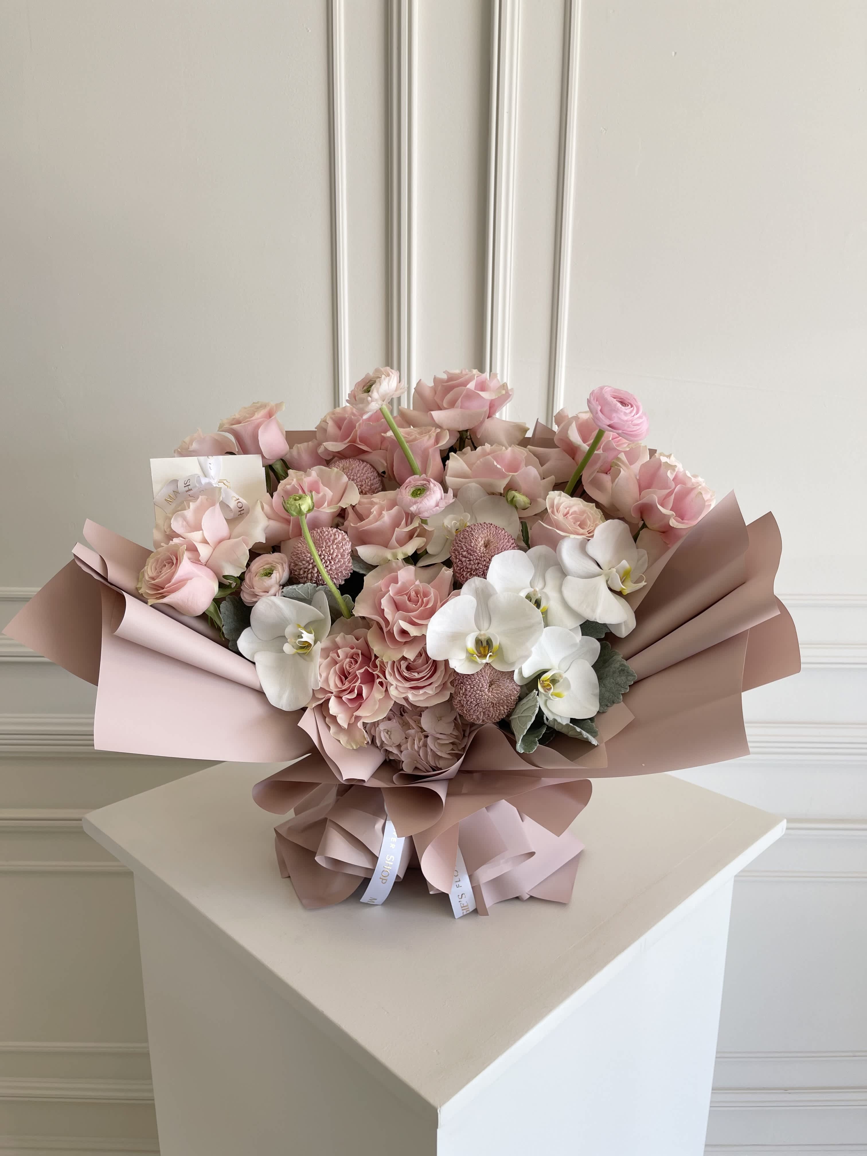 Pink and white bouquet with roses and orchids wrapped in blush paper