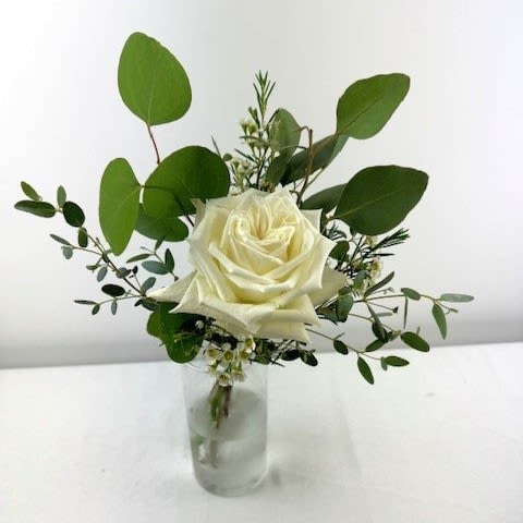 White rose in a small glass vase with greenery
