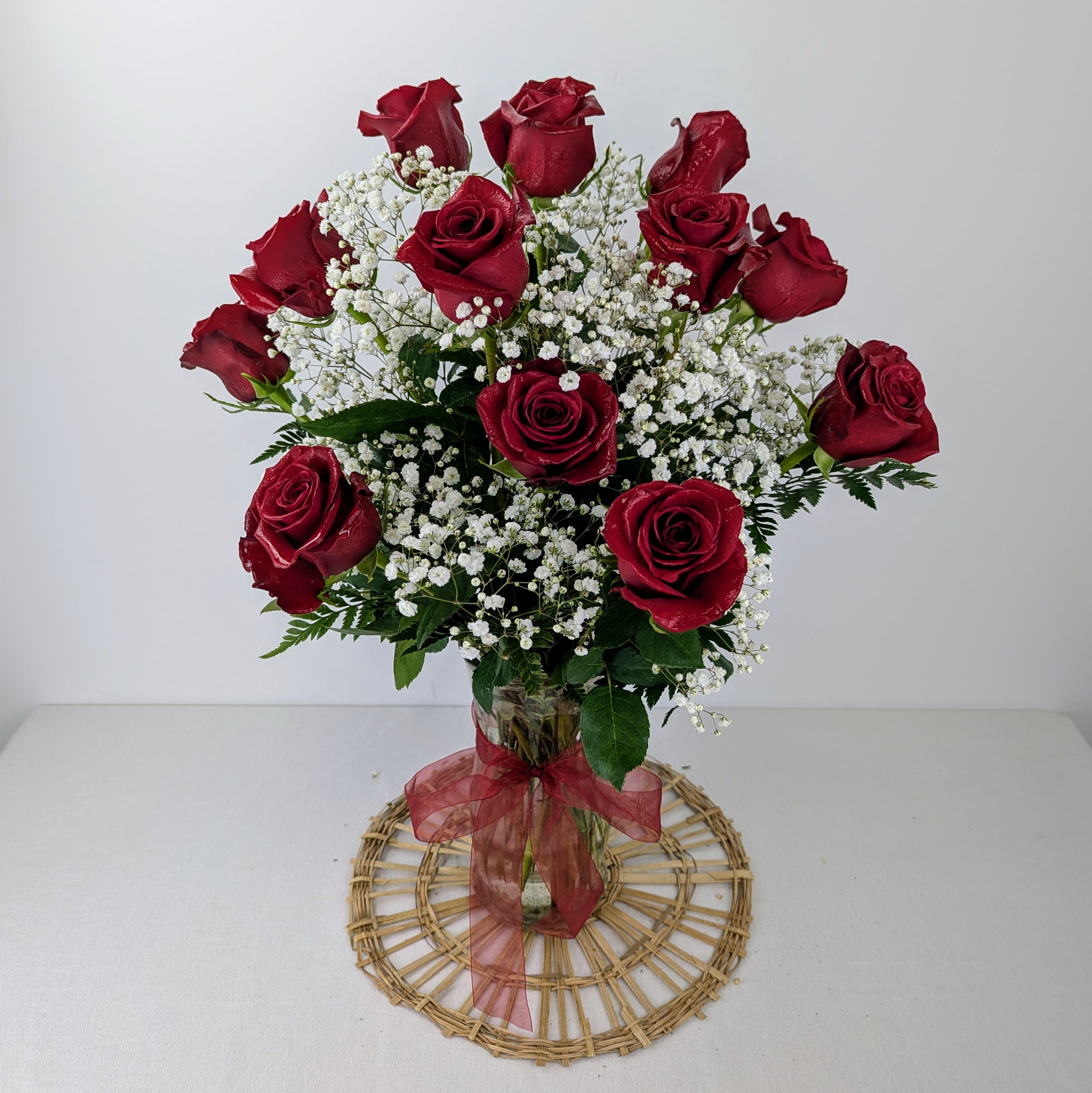 Red roses arranged in a clear glass vase with white baby's breath